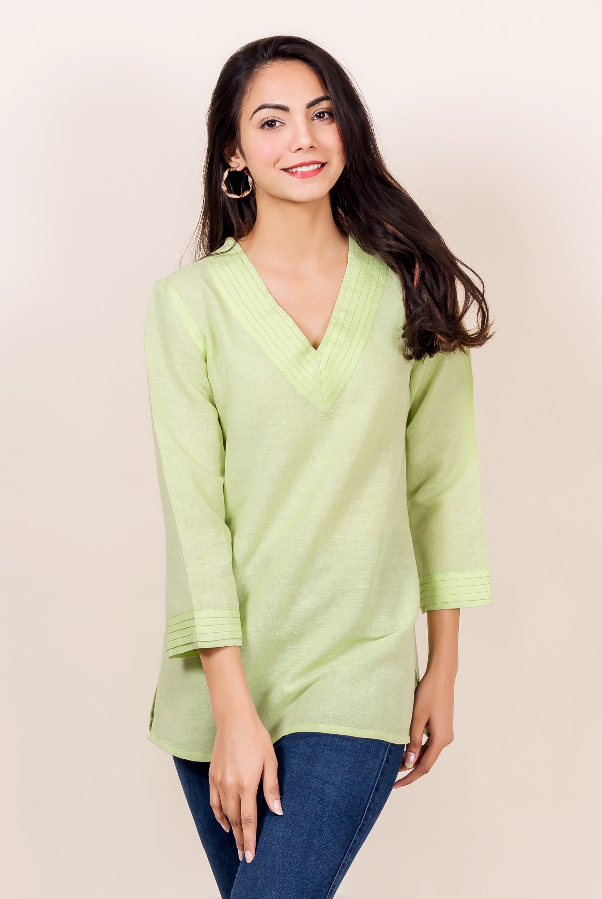 Woman wearing a lime green linen tunic with V-neck and pintuck details.