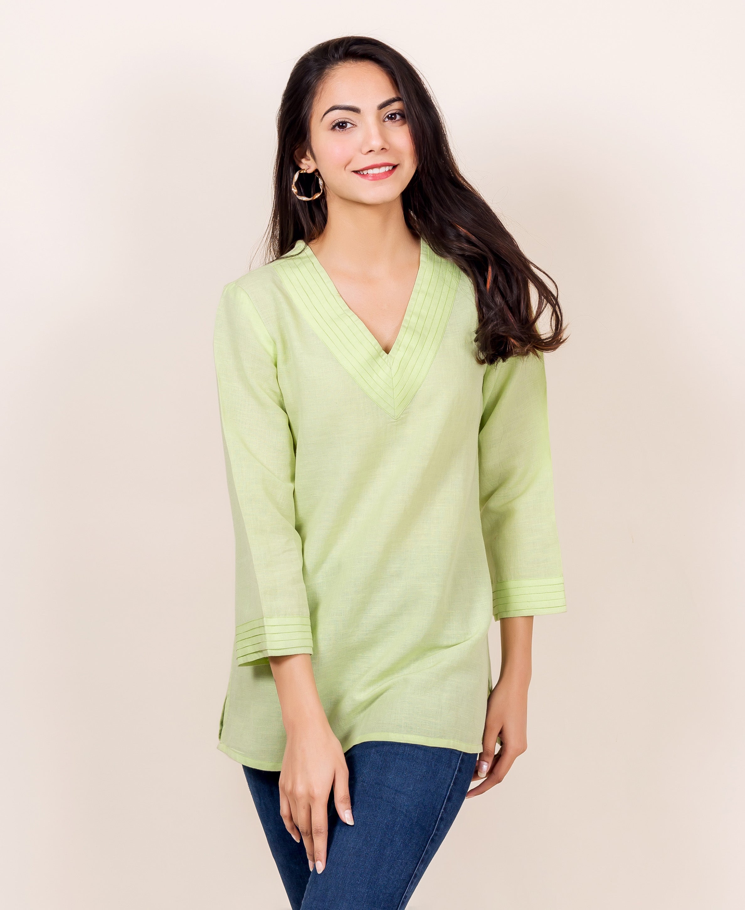 Woman wearing a lime green linen tunic with V-neck and pintuck details.