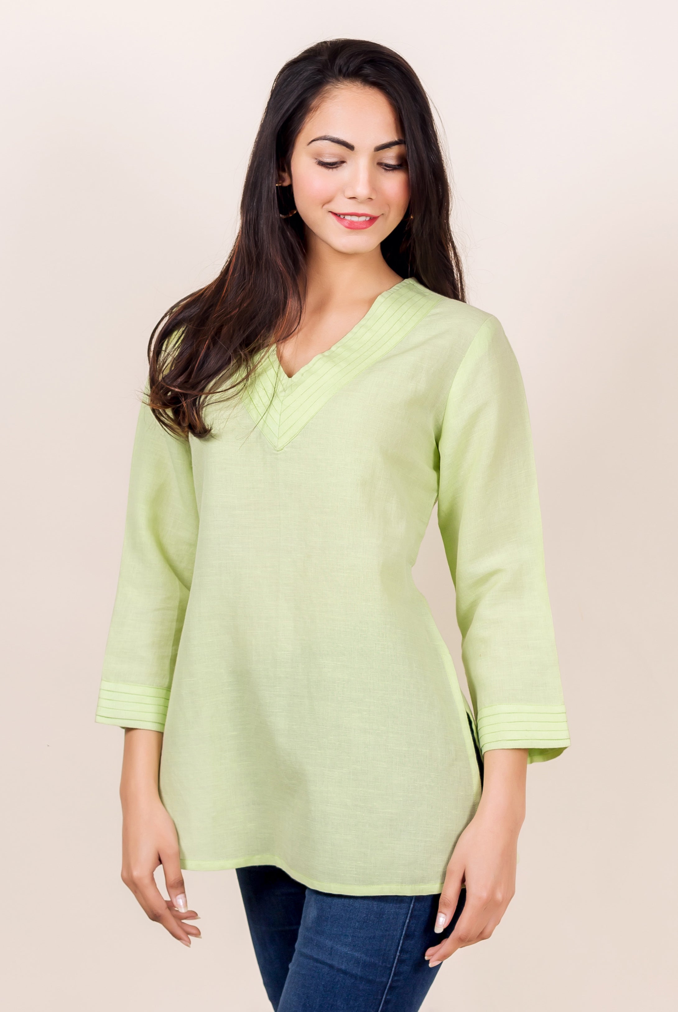 Lime green linen V-neck top with pintuck details on the neckline and sleeves, worn by a model.