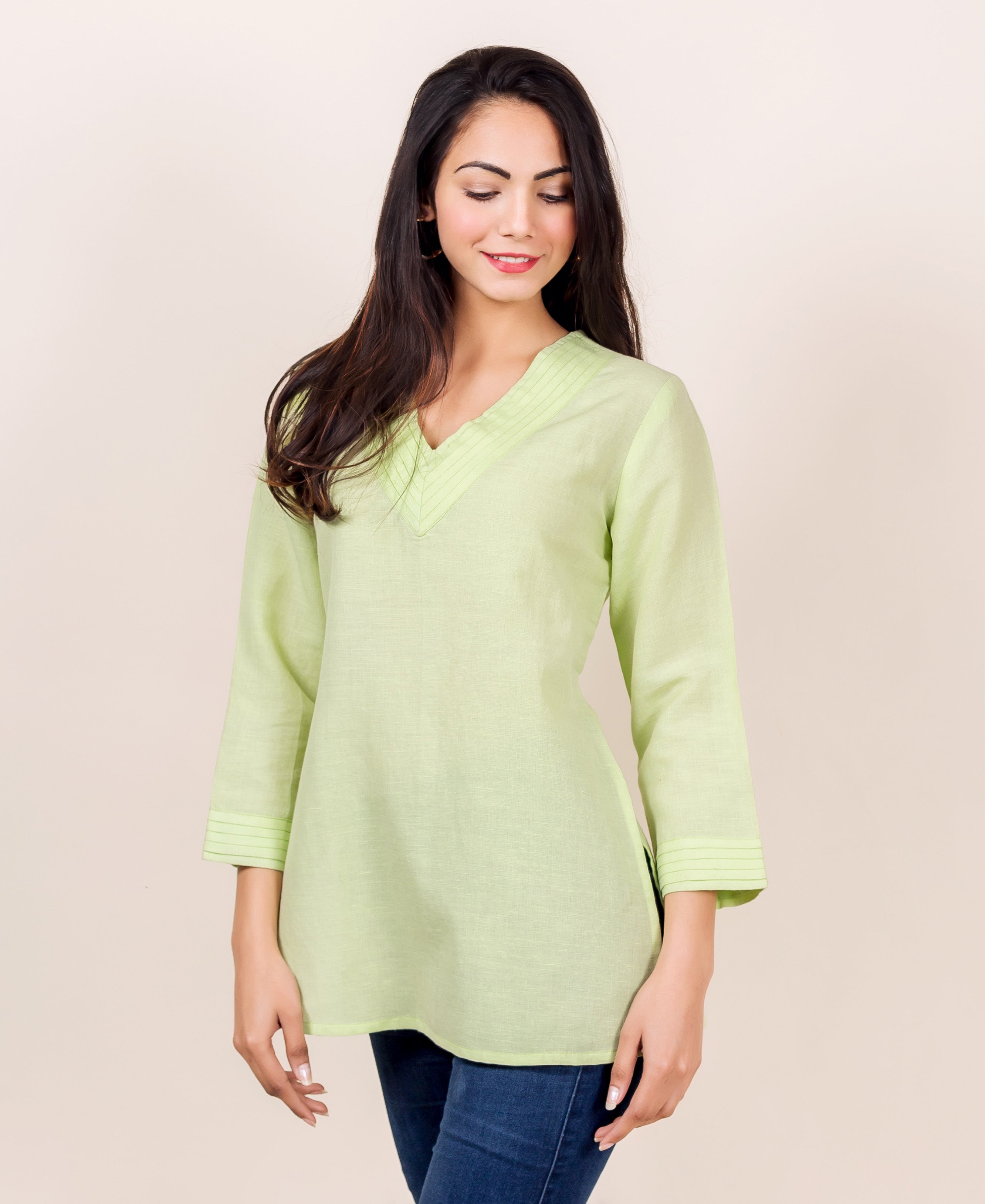 Lime green linen V-neck top with pintuck details on the neckline and sleeves, worn by a model.