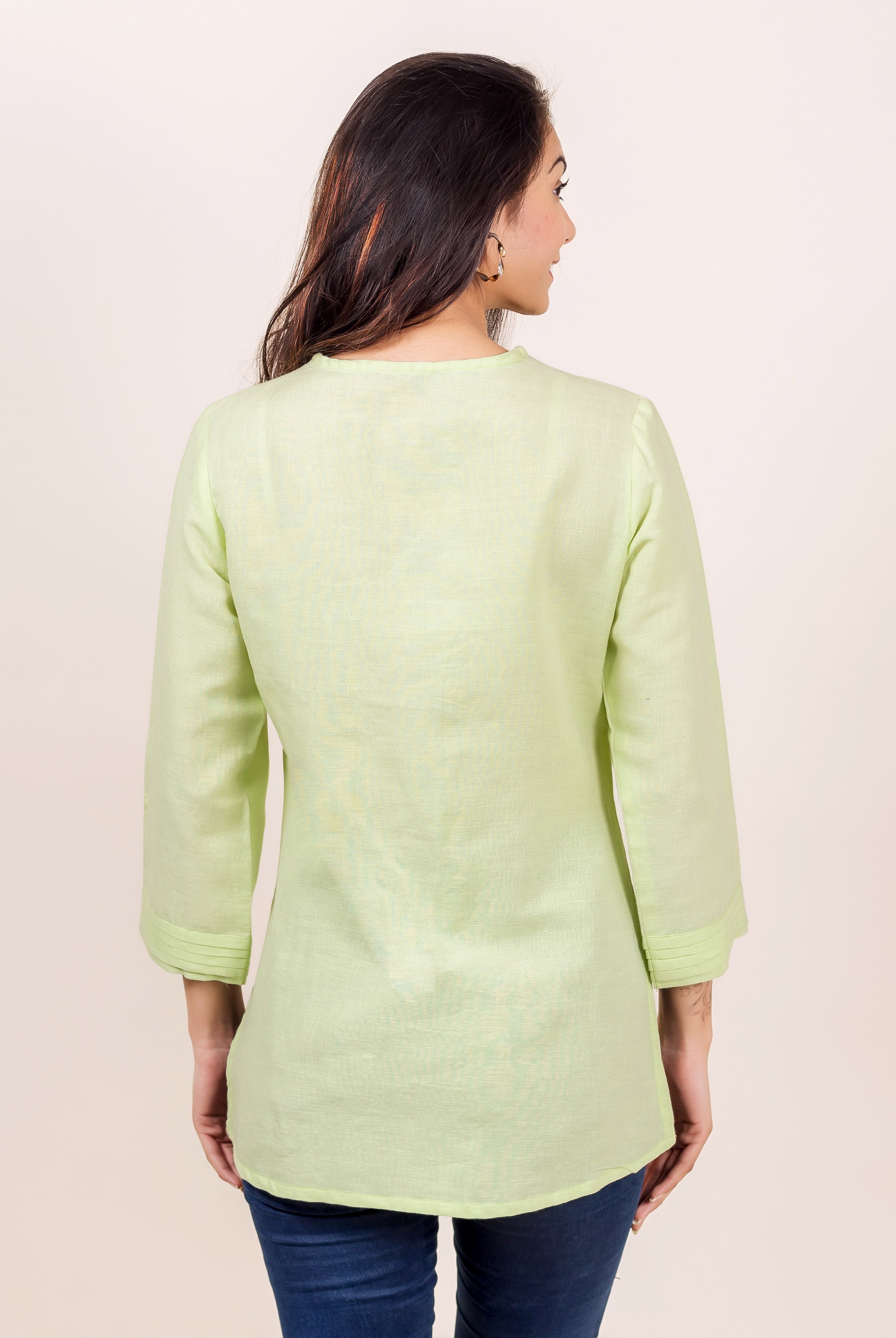 A model wearing a lime green linen top with a subtle block print design.