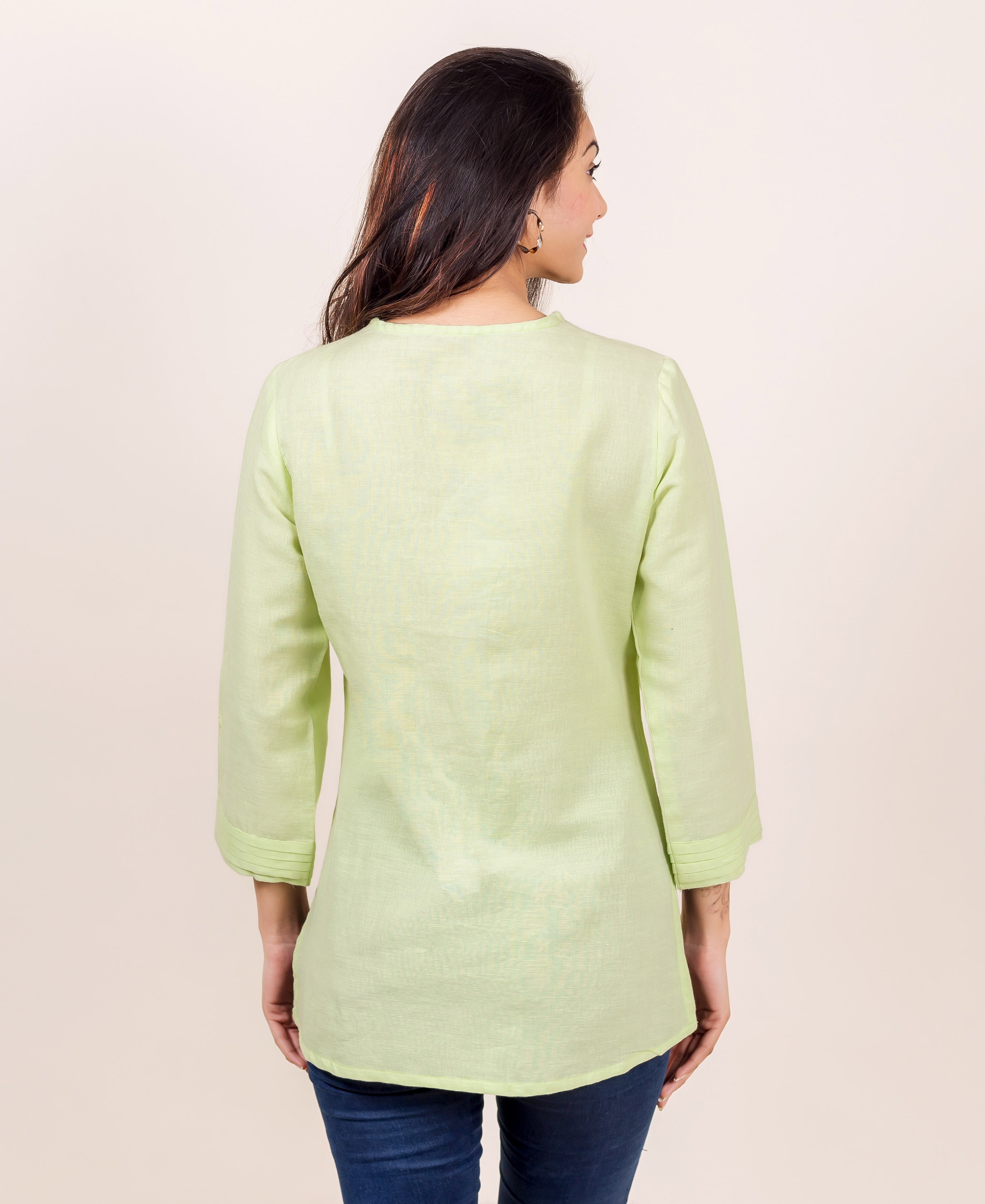 A model wearing a lime green linen top with a subtle block print design.