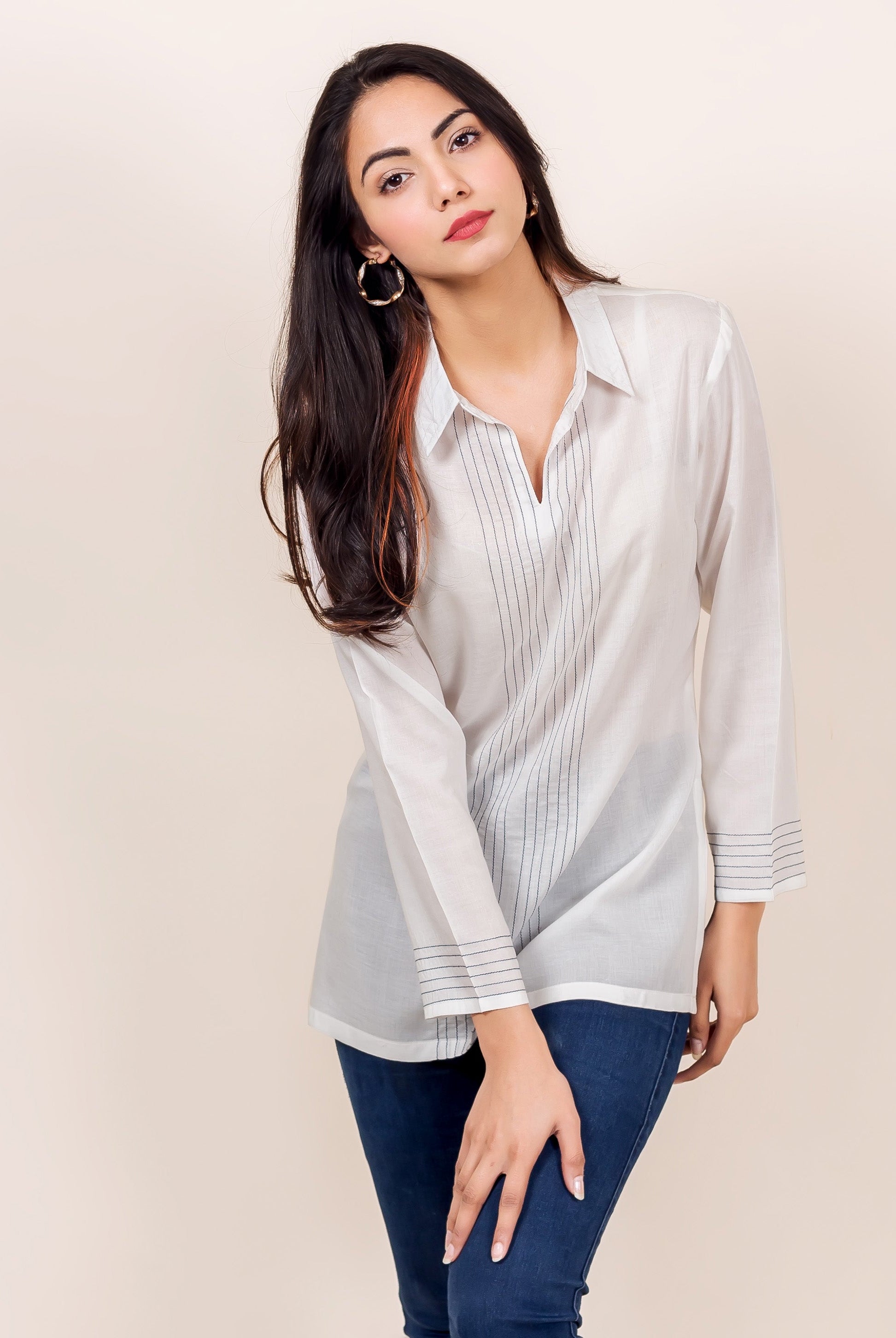 Angled model in white shirt collar top with dark vertical embroidered lines.