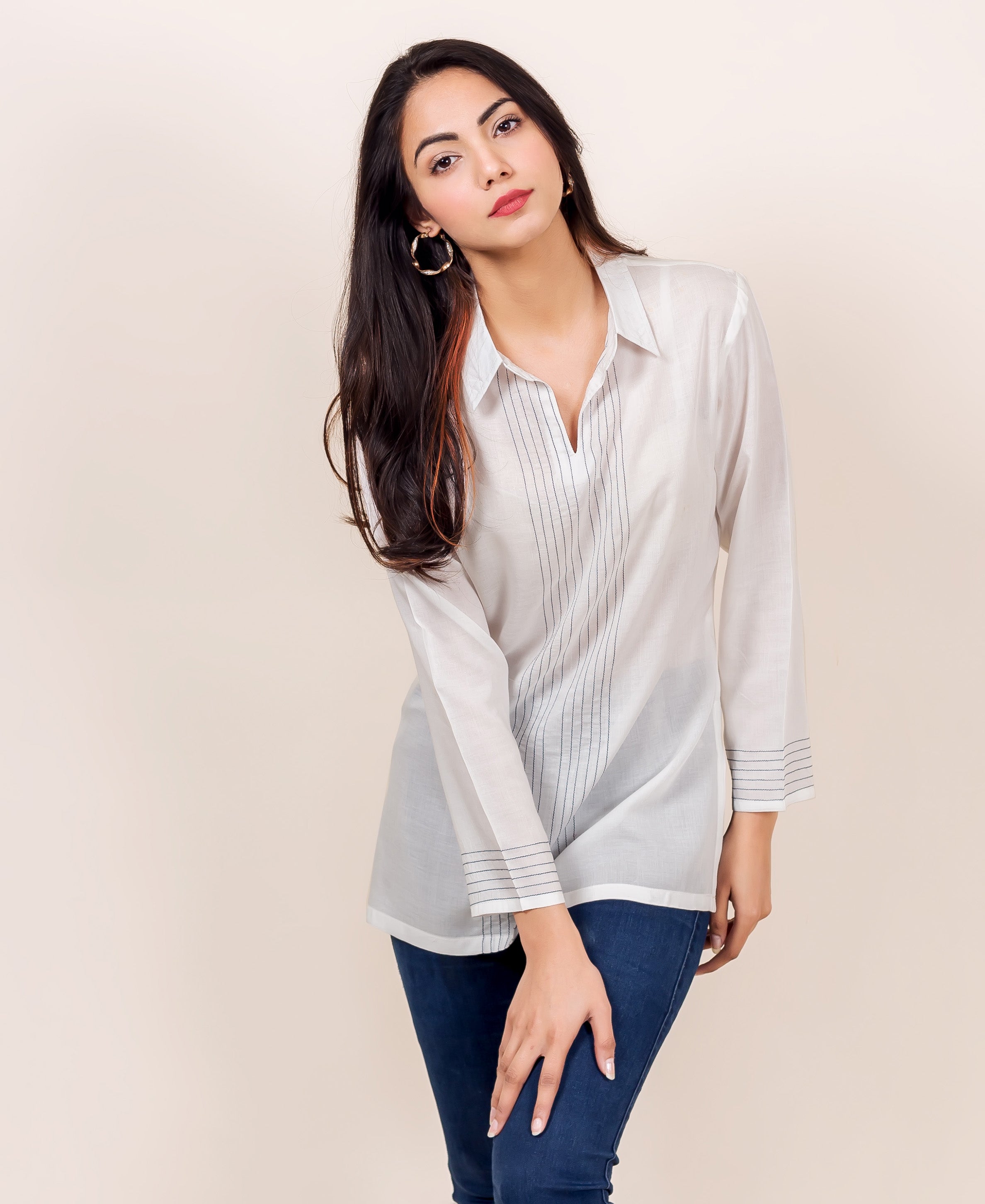 Angled model in white shirt collar top with dark vertical embroidered lines.