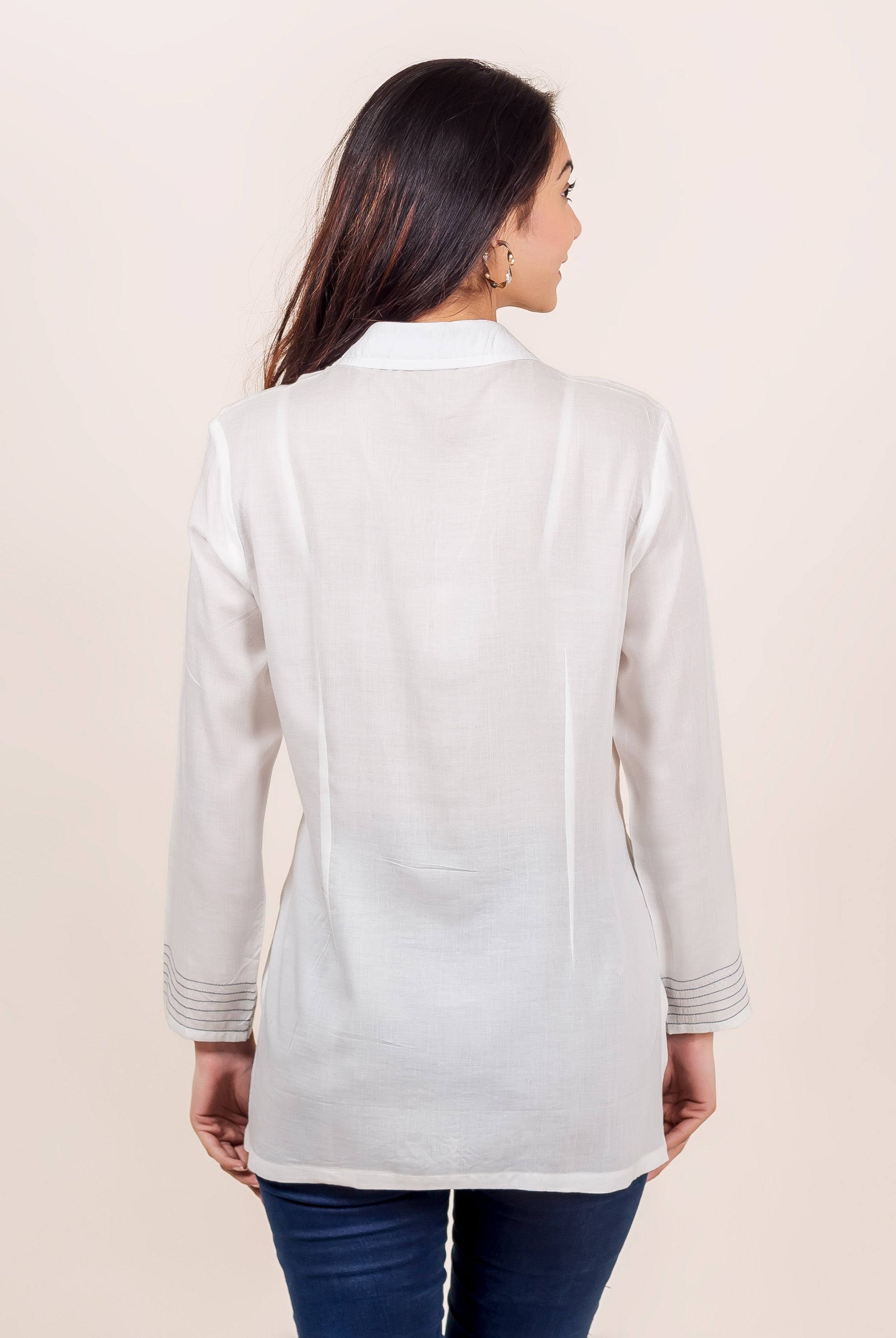 Back view of model in white top with shirt collar and grey embroidered cuffs.