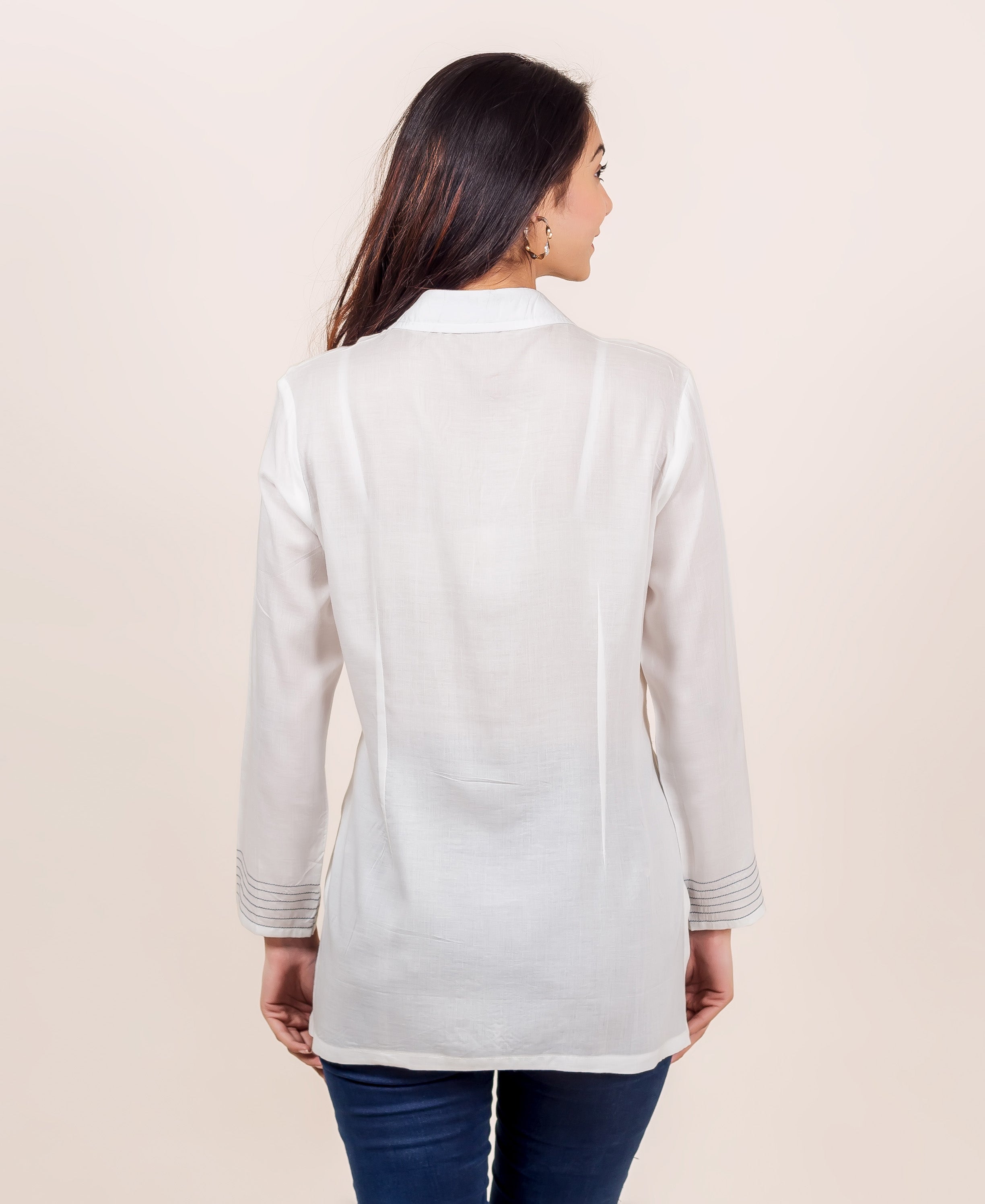 Back view of model in white top with shirt collar and grey embroidered cuffs.