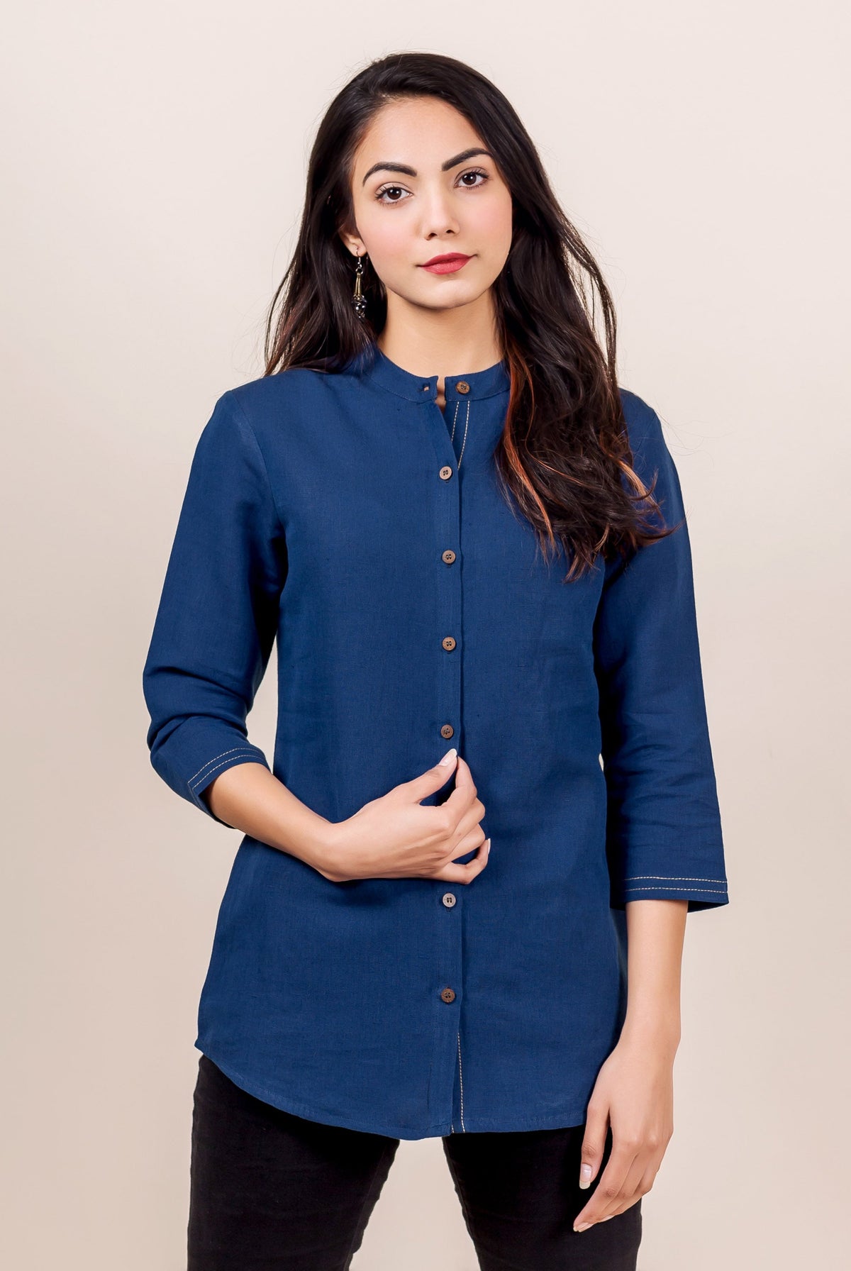 Front view of model in an indigo linen button-down shirt with band collar and white stitching.