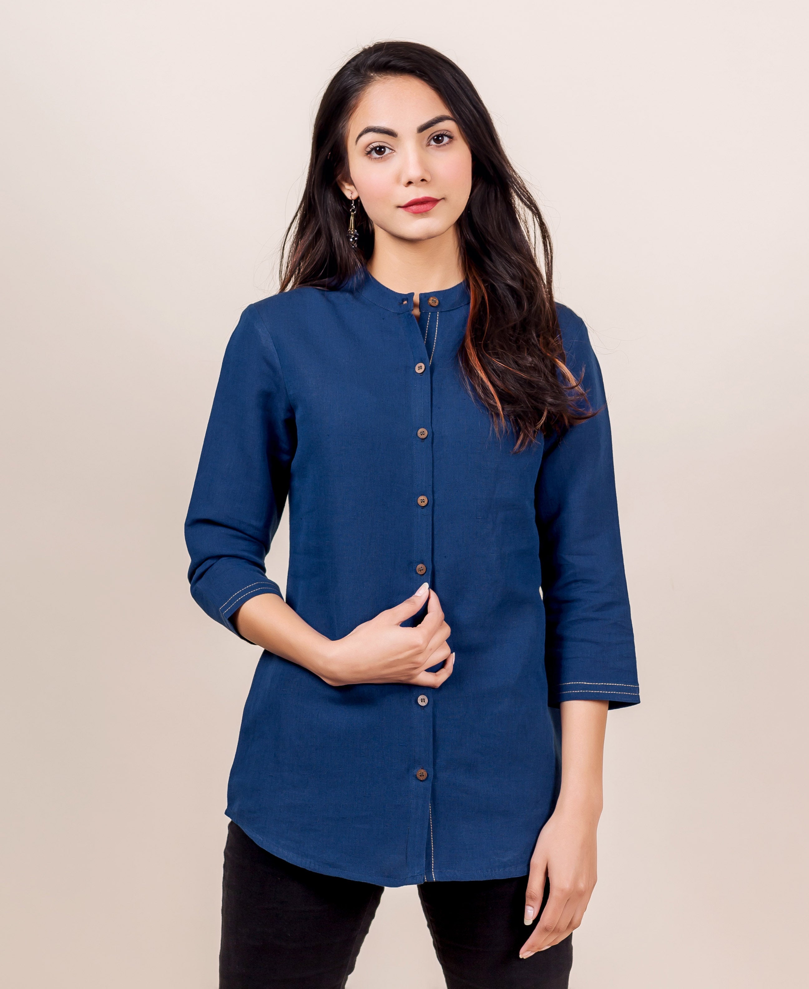 Front view of model in an indigo linen button-down shirt with band collar and white stitching.