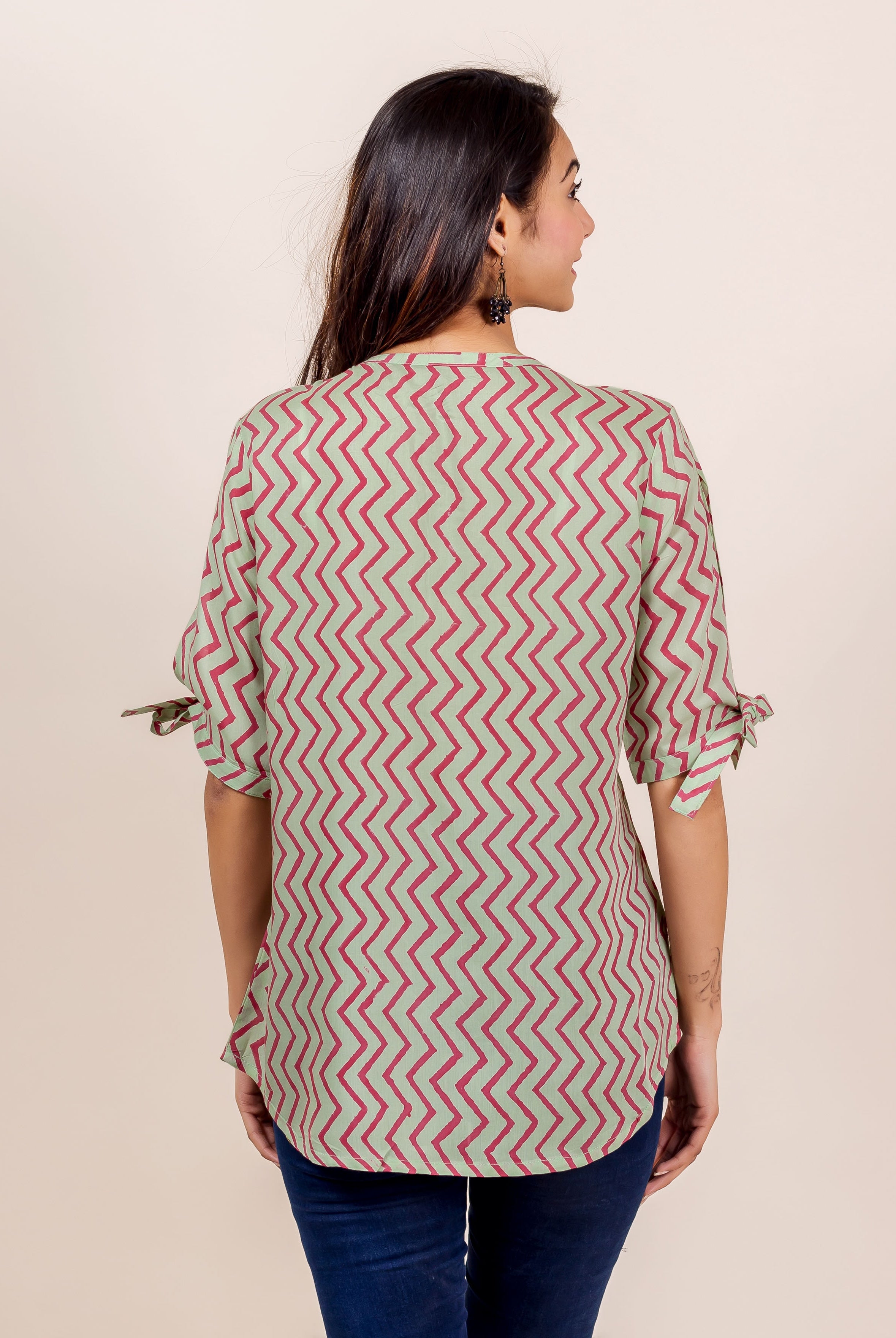 Back view of model wearing a mint green and pink striped top with tied sleeves.