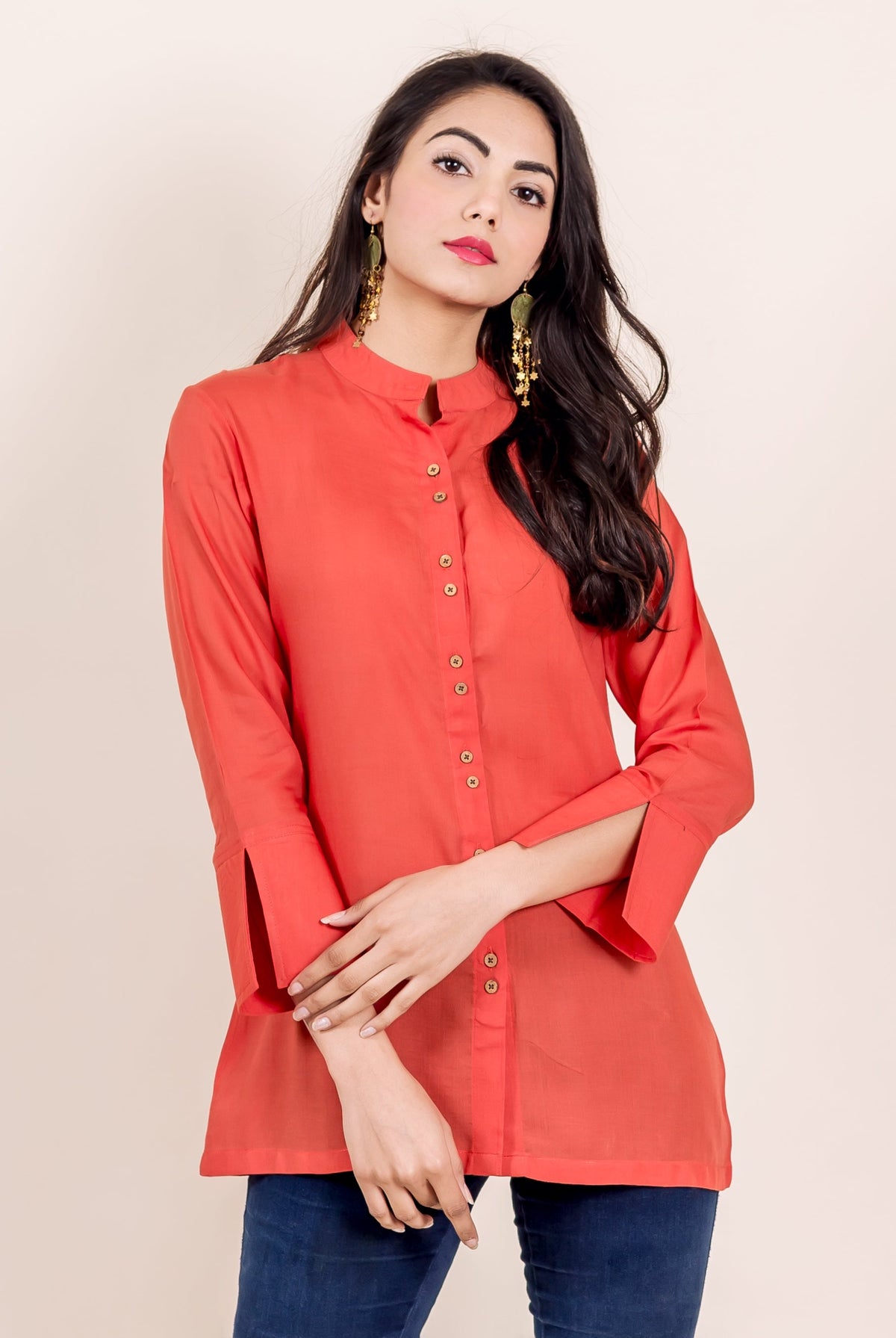 Woman modeling a rust shirt with a mandarin collar and distinctive slit sleeves, front view.