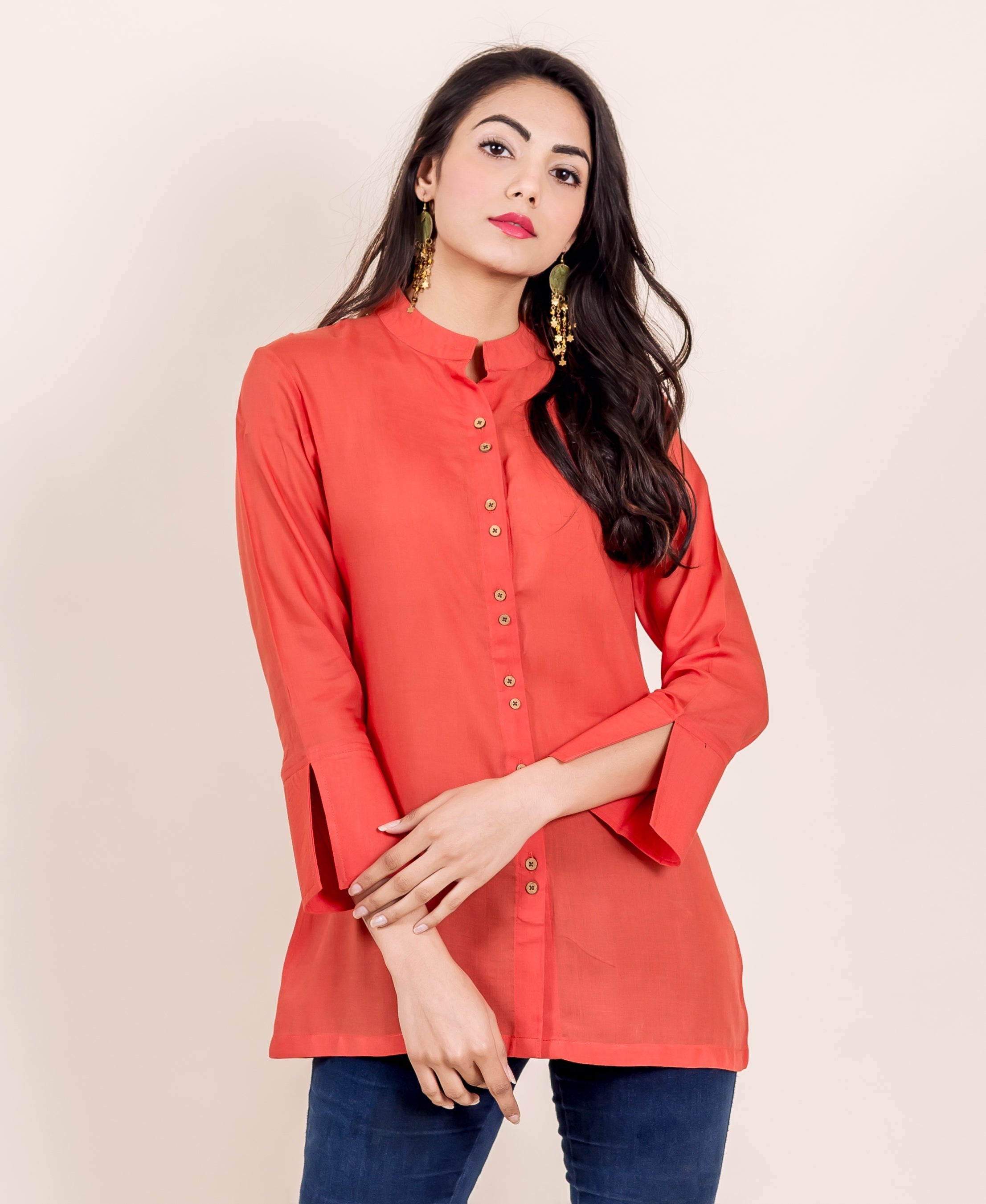 Woman modeling a rust shirt with a mandarin collar and distinctive slit sleeves, front view.