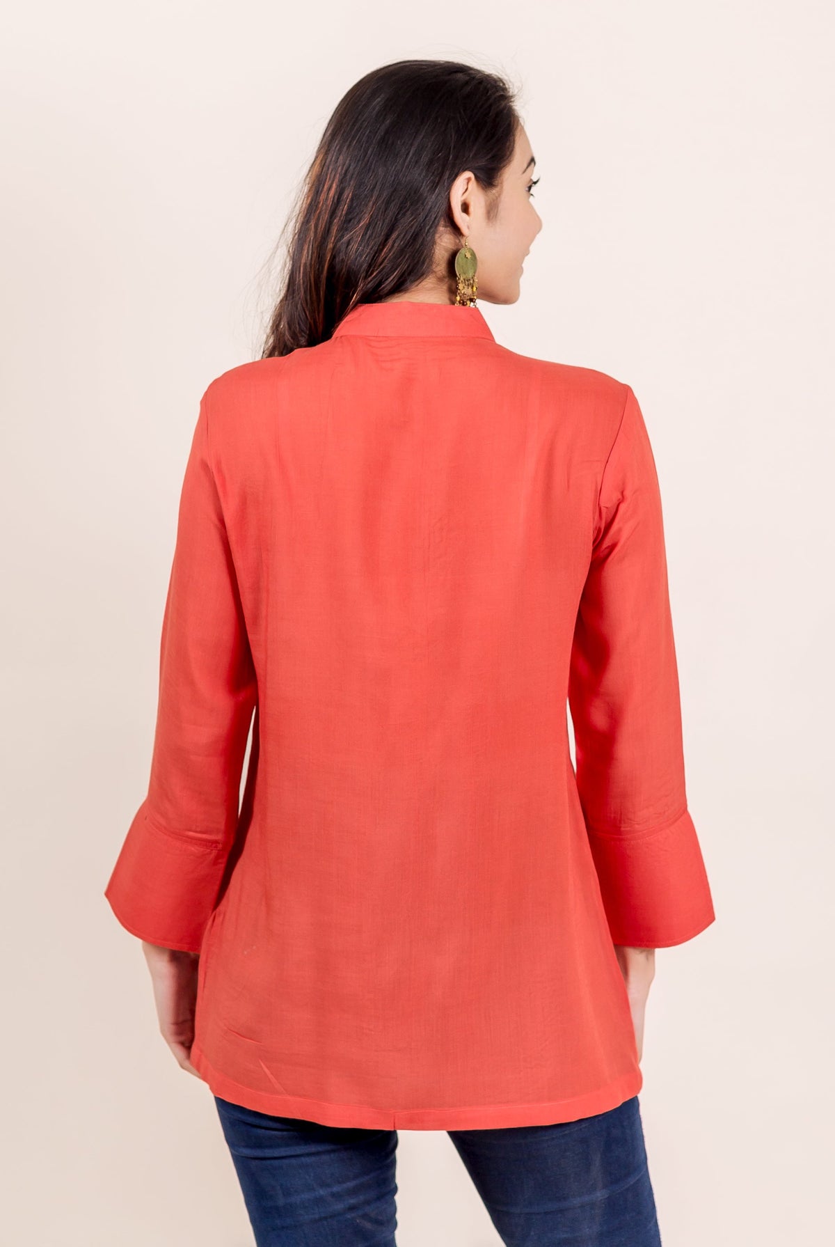 Back view of model in a rust mandarin collar tunic with flared sleeves.