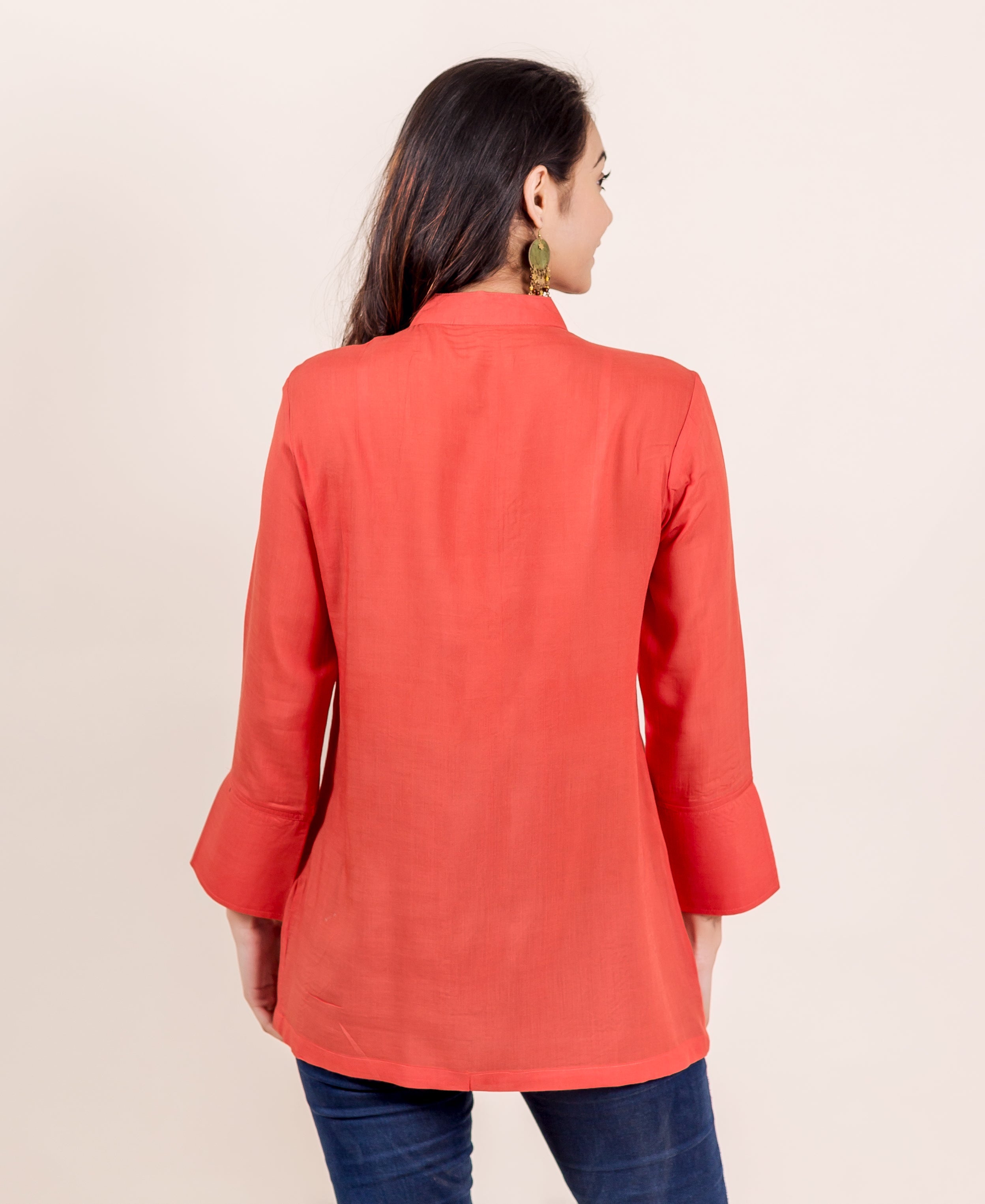 Back view of model in a rust mandarin collar tunic with flared sleeves.
