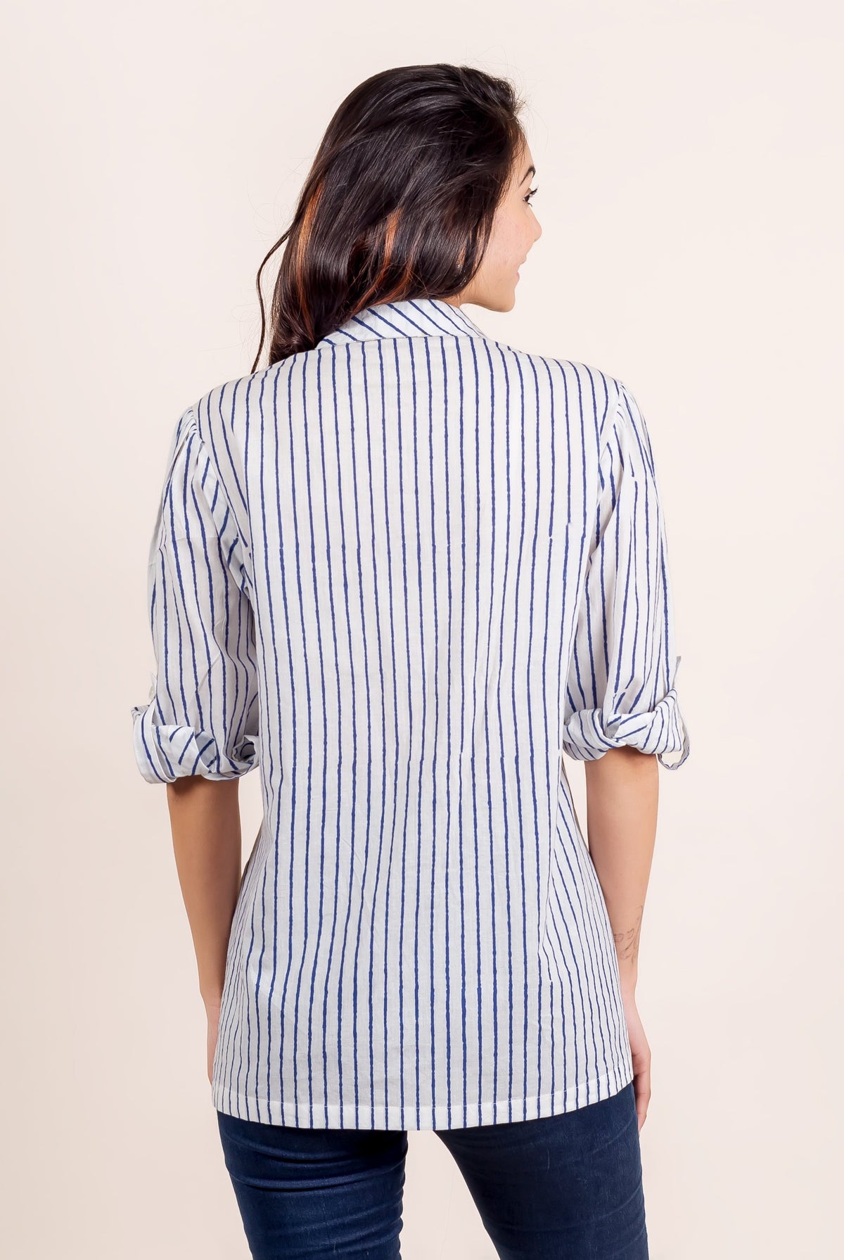 Rear view of model in white and blue striped shirt top with rolled sleeves.