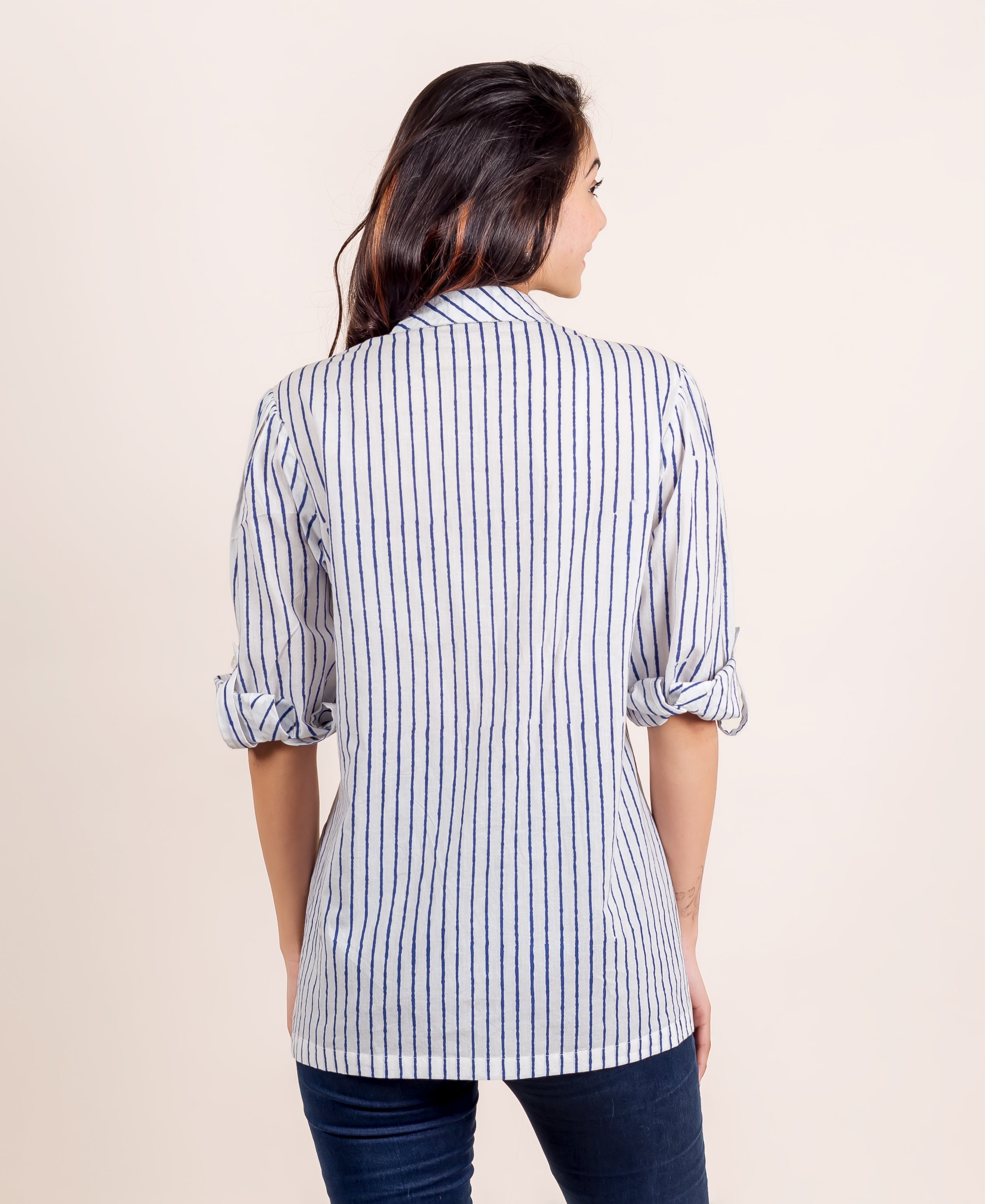 Rear view of model in white and blue striped shirt top with rolled sleeves.