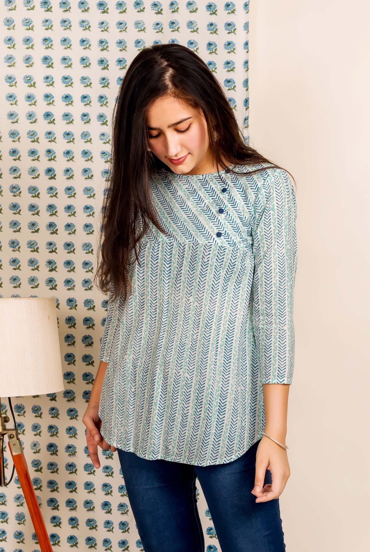 Front view, model in a blue hand block printed ethnic top with chevron patterns.
