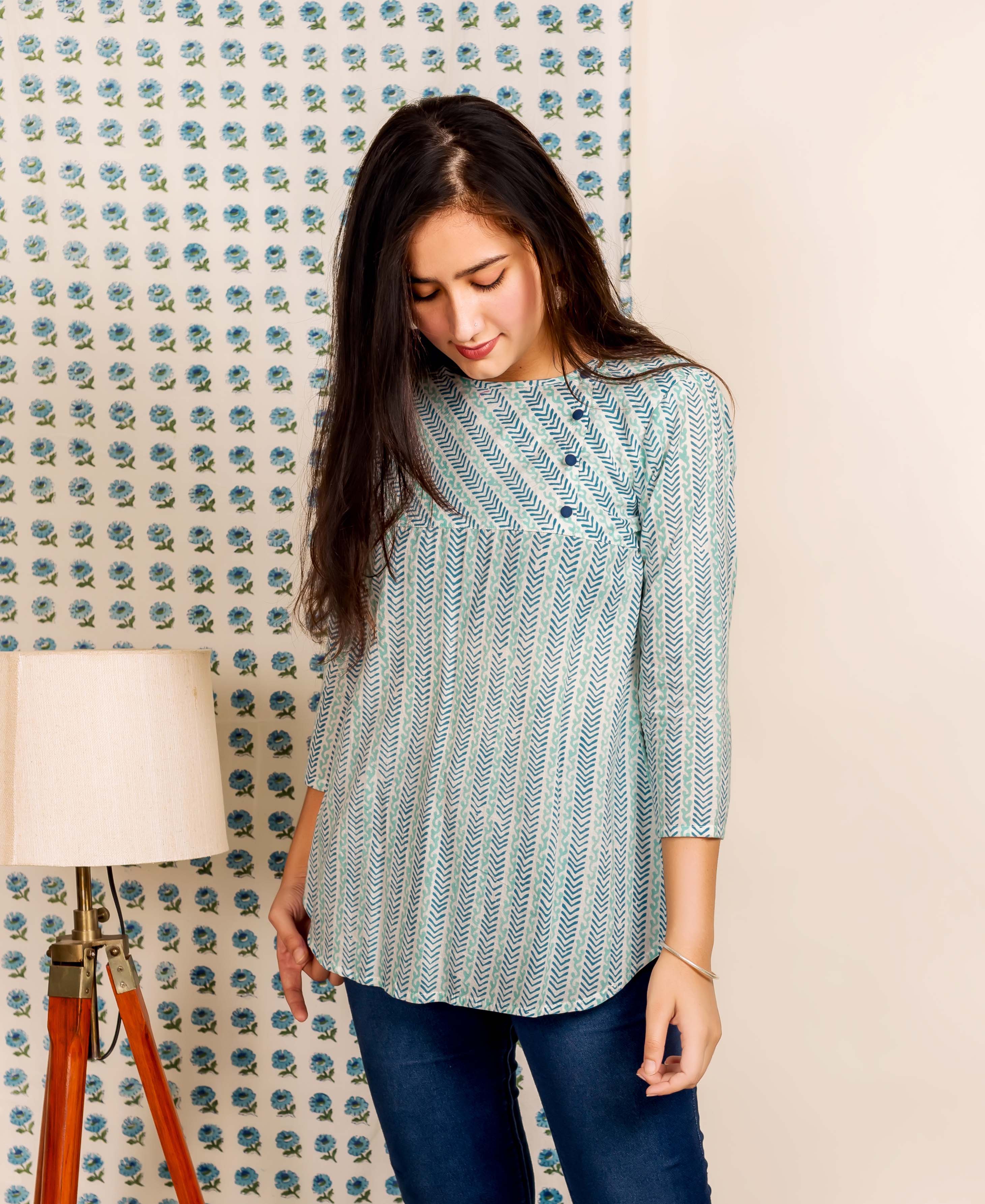 Front view, model in a blue hand block printed ethnic top with chevron patterns.