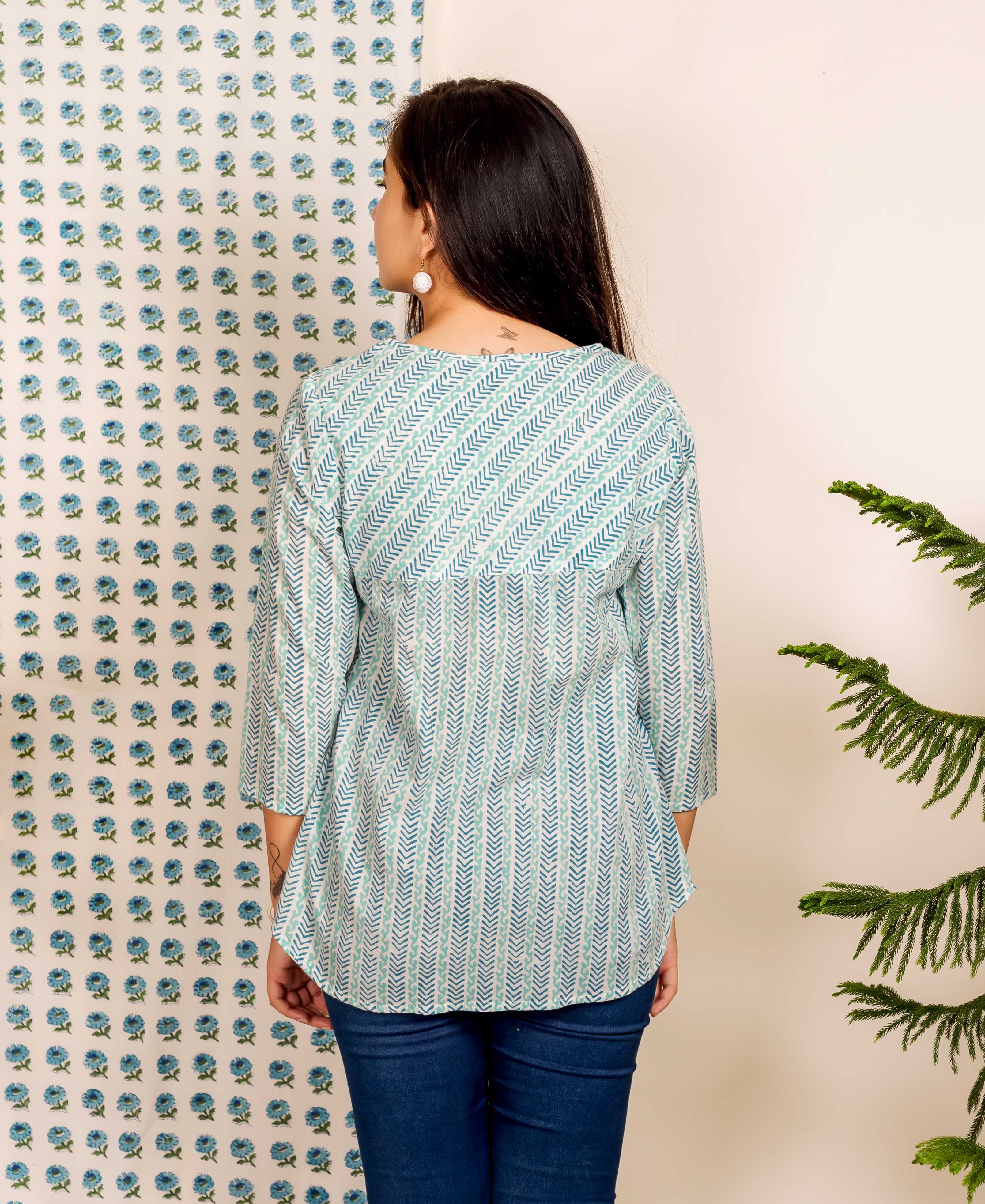 Back view of model wearing blue and white chevron hand block printed ethnic top and jeans.