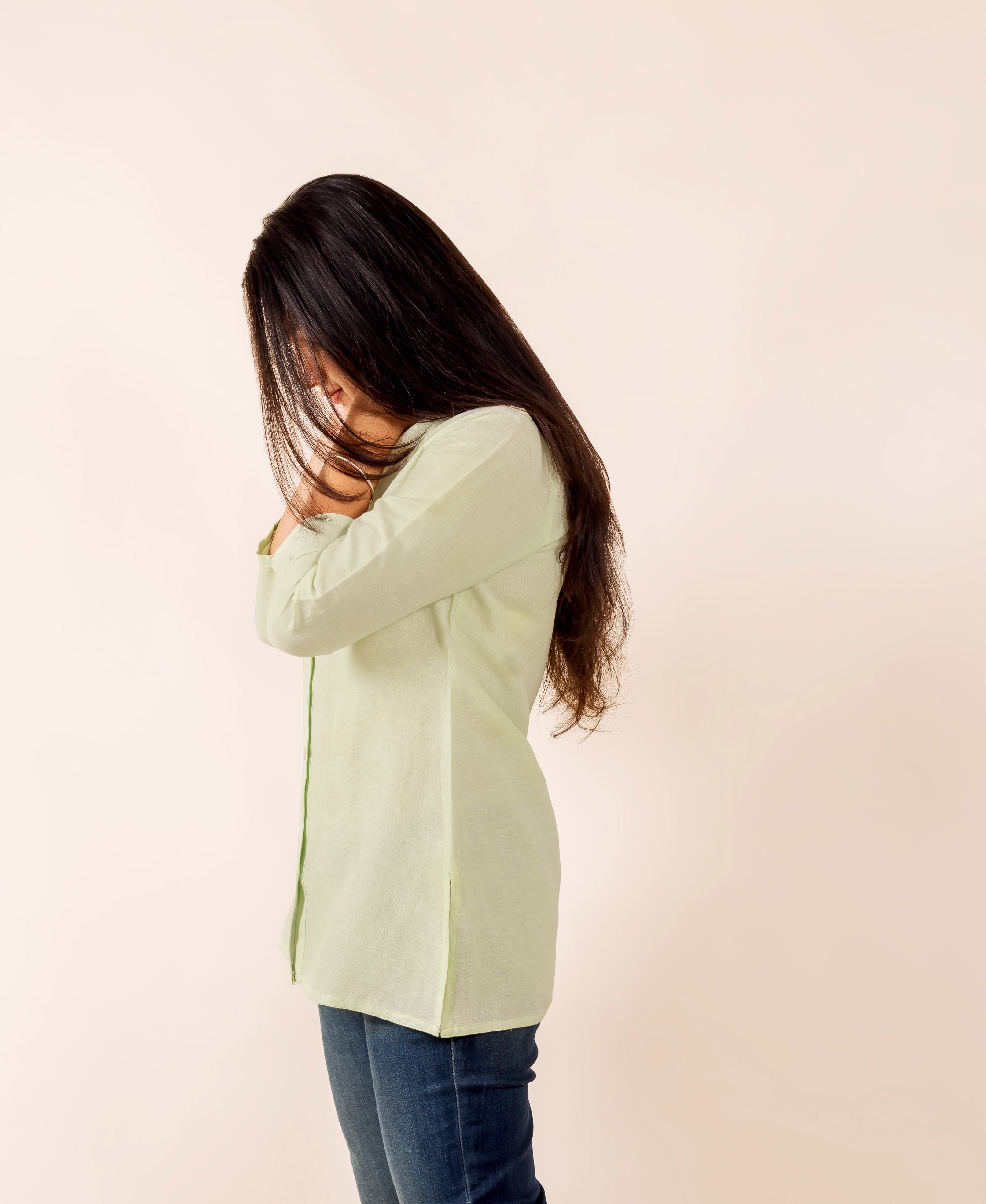 Model wearing lime button down linen top in side profile with long dark hair.