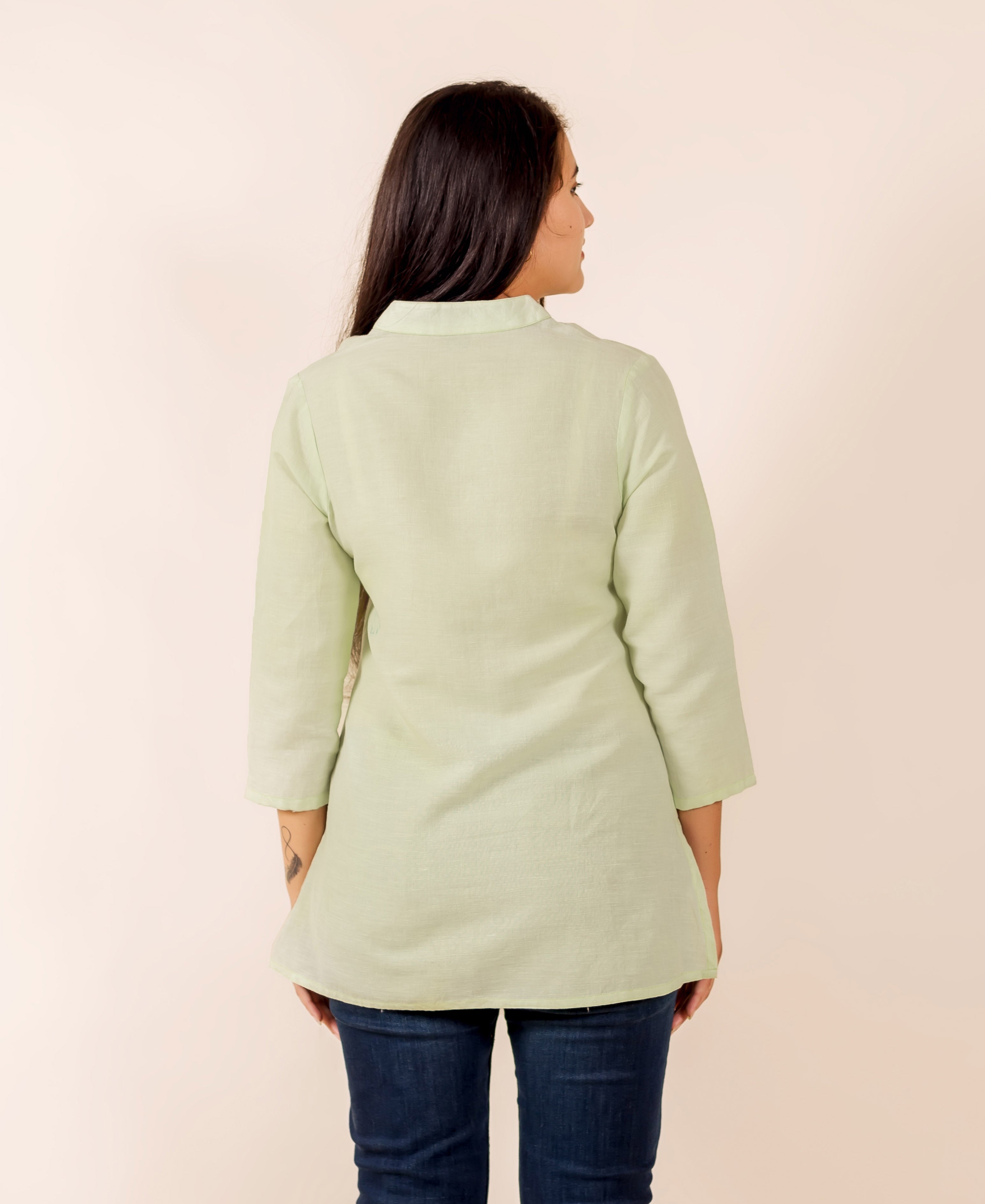 Back view of a woman wearing a lime green collared tunic top with three-quarter sleeves.