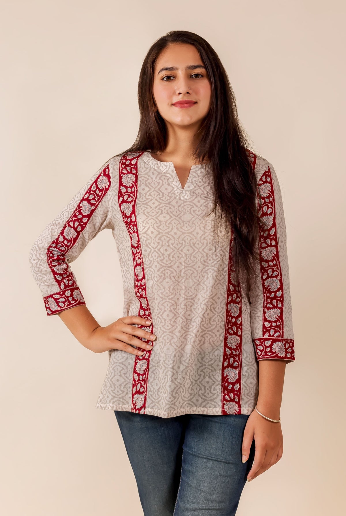 Woman modeling off-white top with grey geometric pattern and maroon floral block-printed borders.