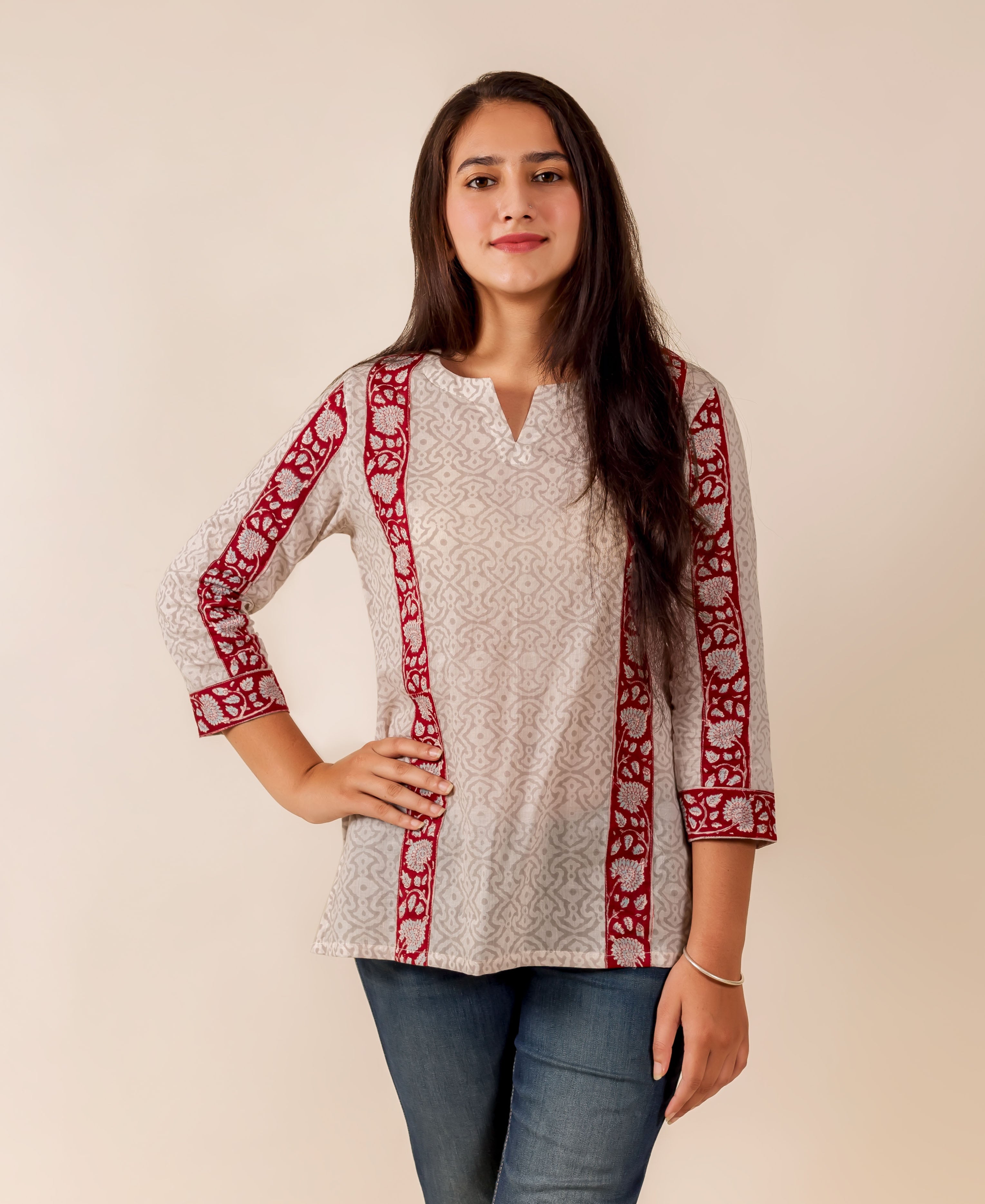 Woman modeling off-white top with grey geometric pattern and maroon floral block-printed borders.