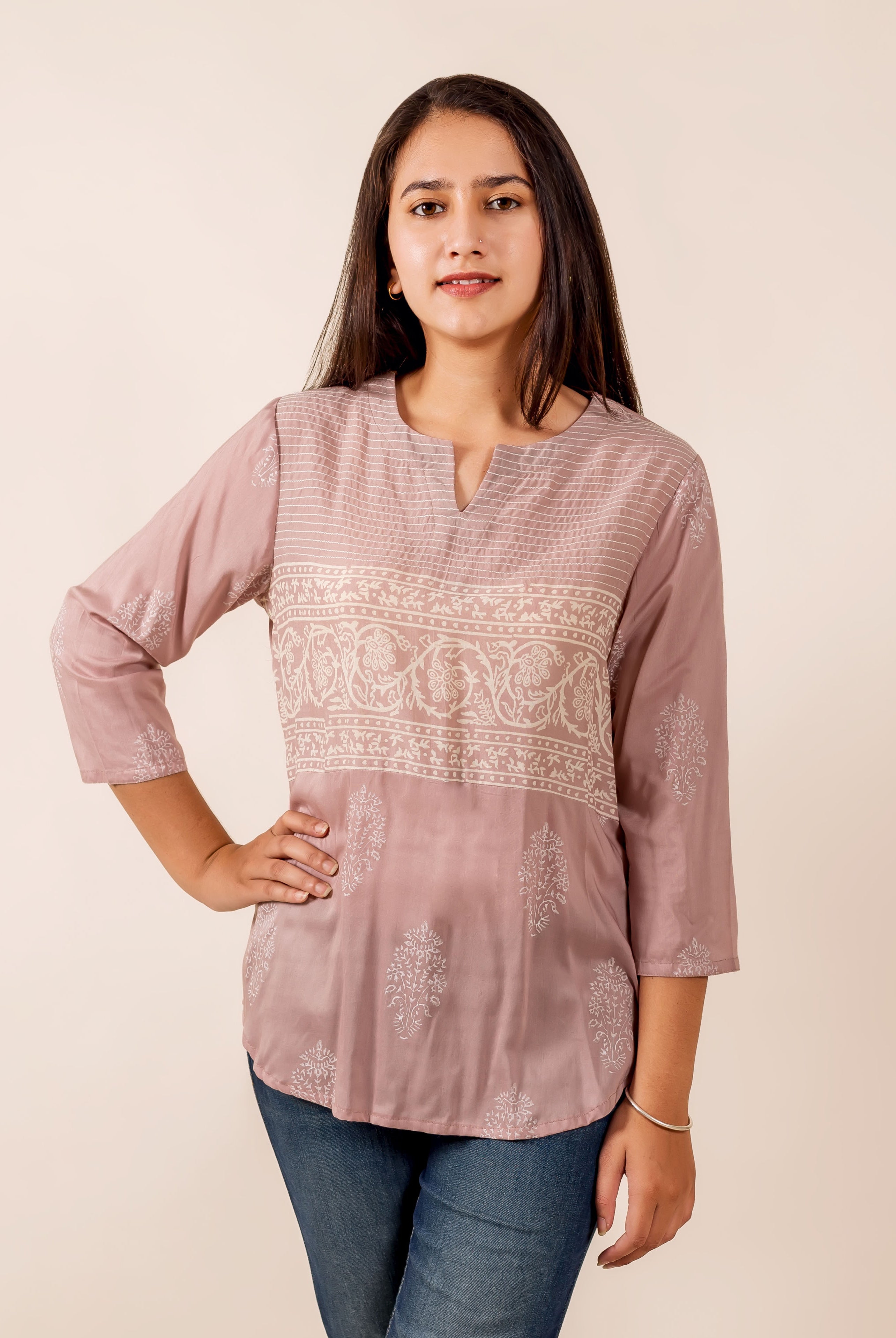 Woman models dusty pink hand-block printed top with white thread work, paired with jeans.