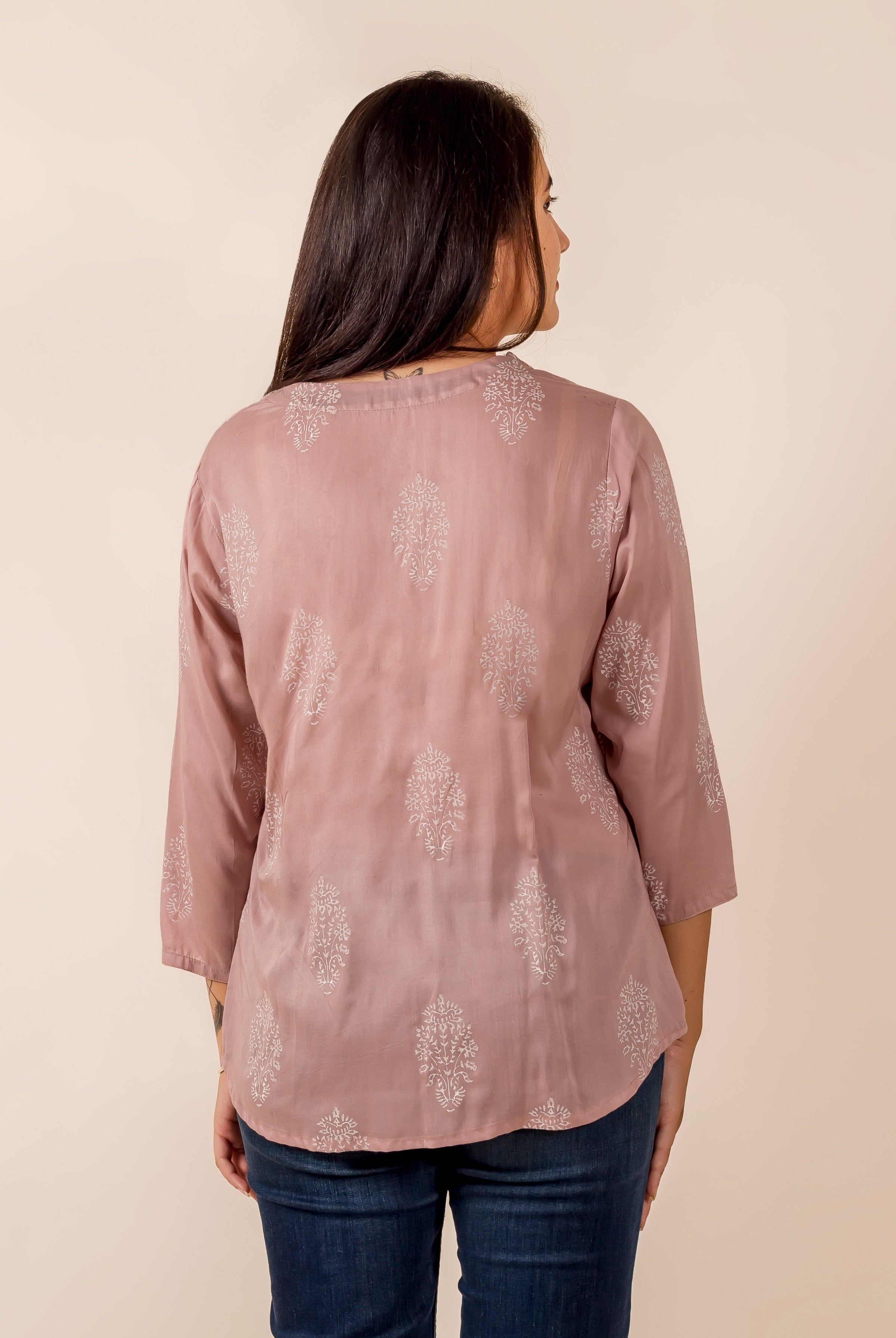 Dusty pink top with light ethnic thread work pattern, seen from back on model.
