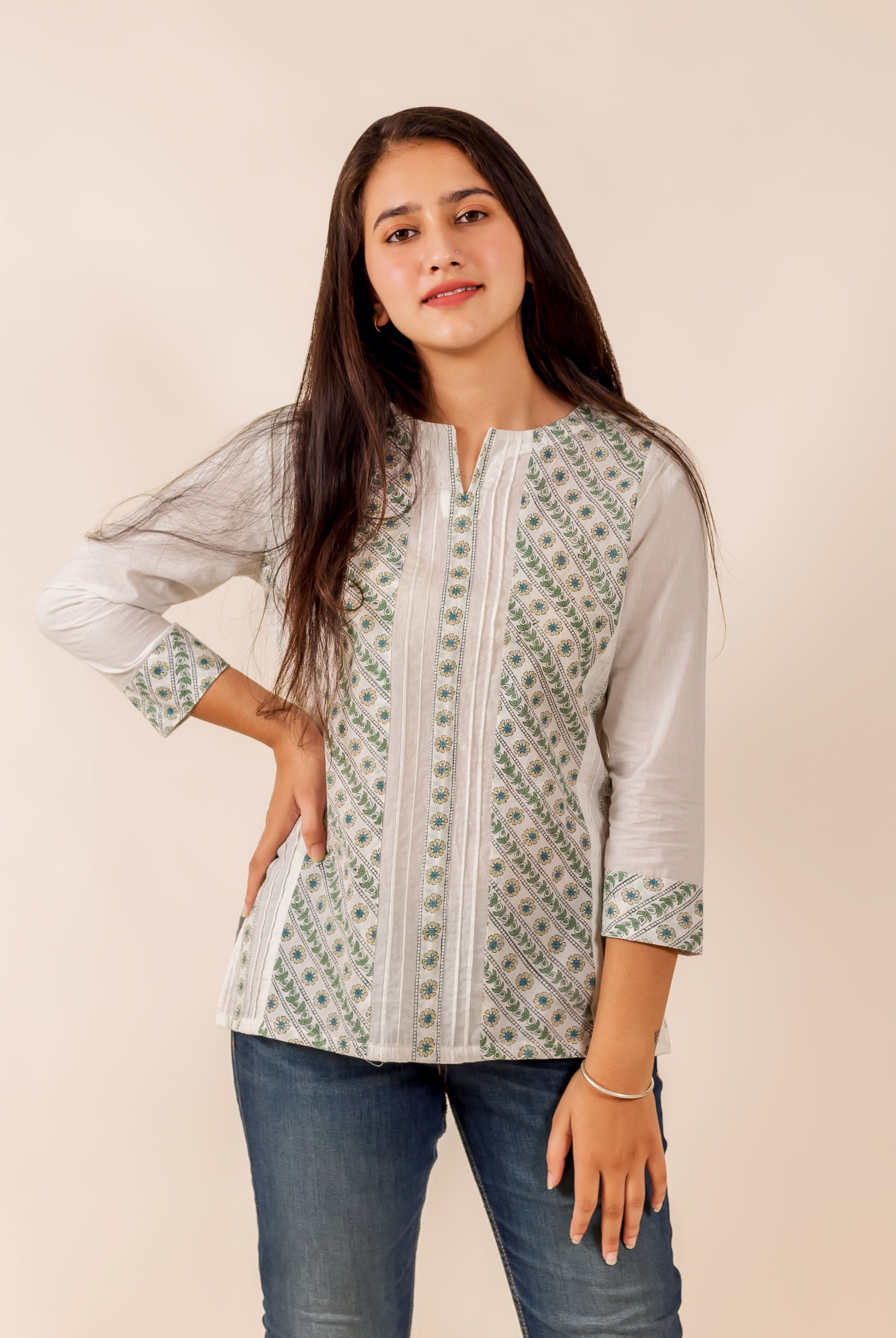 Model wearing a white and green hand block printed pintuck top and blue jeans.