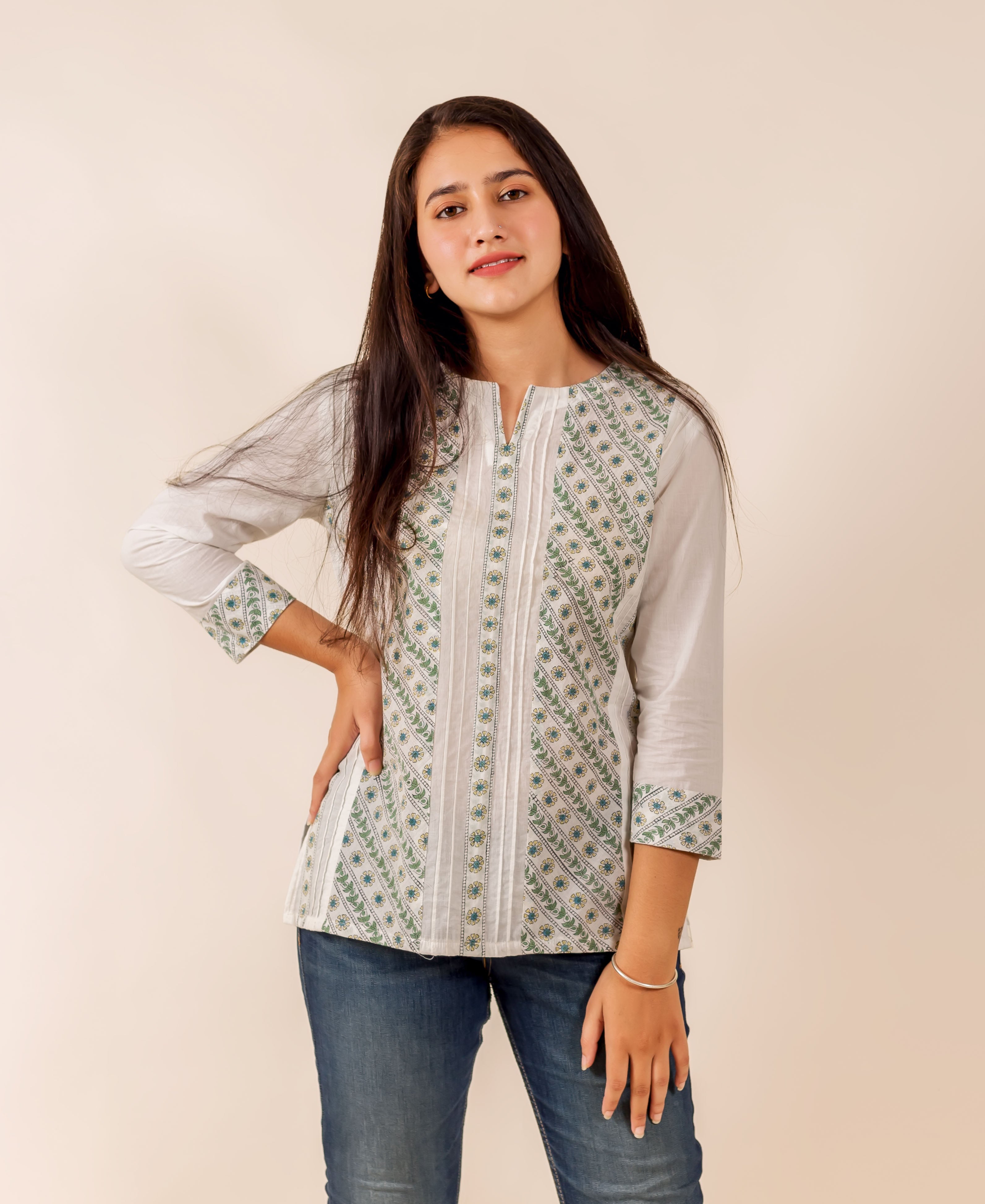 Model wearing a white and green hand block printed pintuck top and blue jeans.