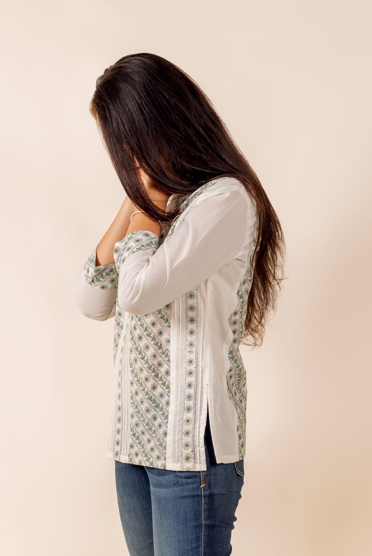 Side view of model wearing white, green, blue hand block printed pintuck top and jeans.