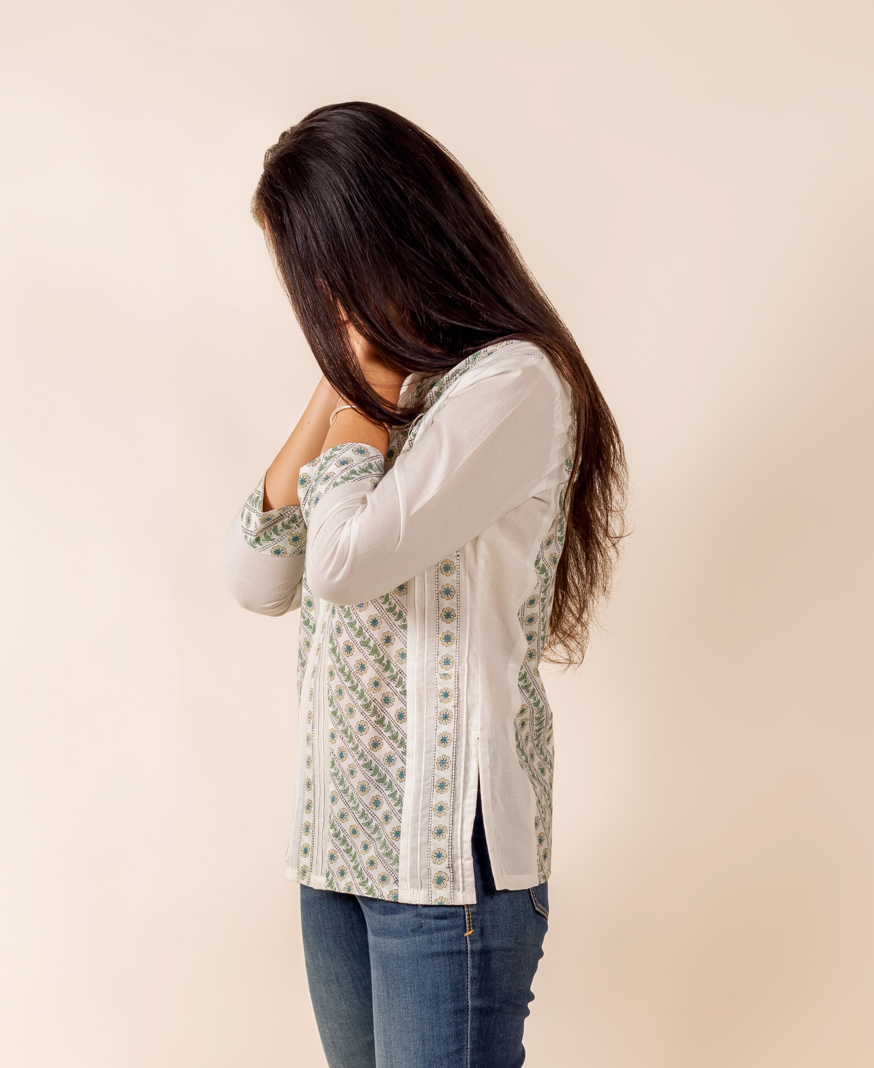 Side view of model wearing white, green, blue hand block printed pintuck top and jeans.