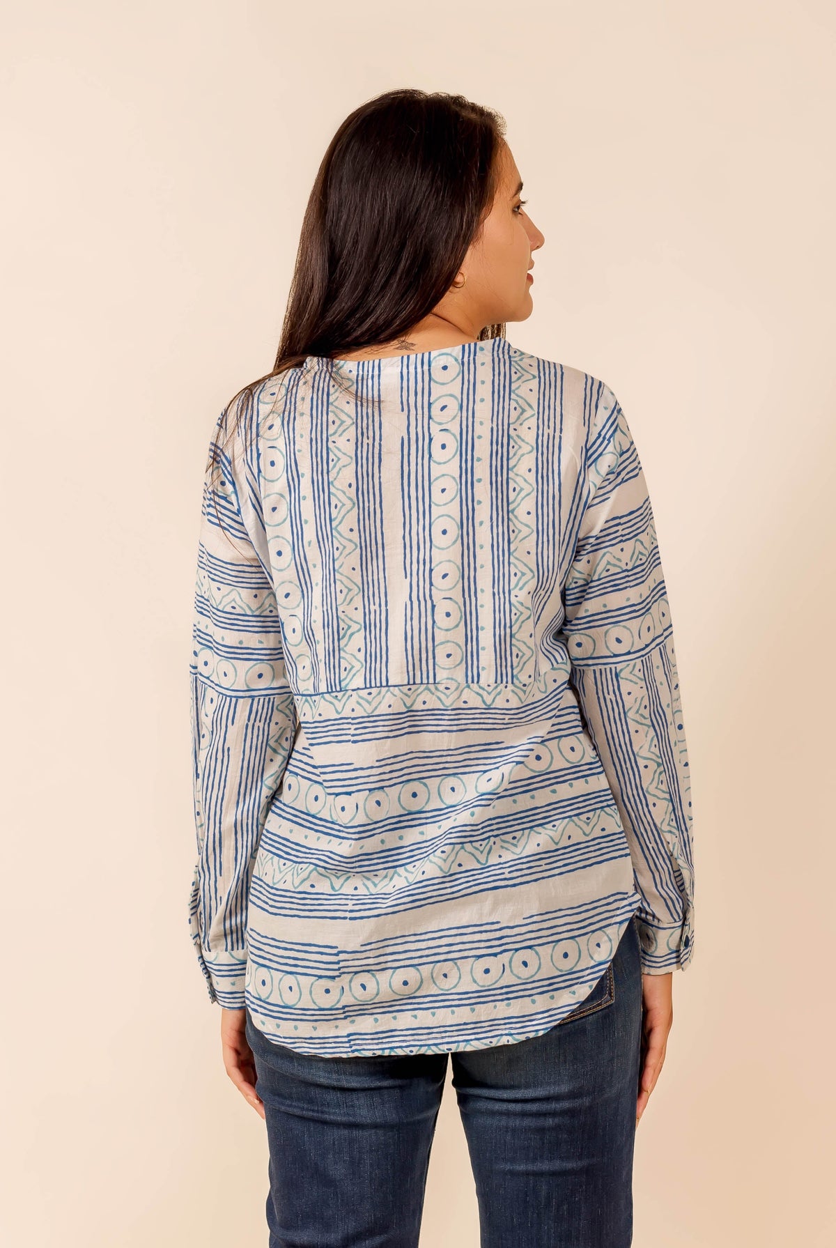 Rear view of model in white and blue ethnic block-printed long-sleeve shirt top.