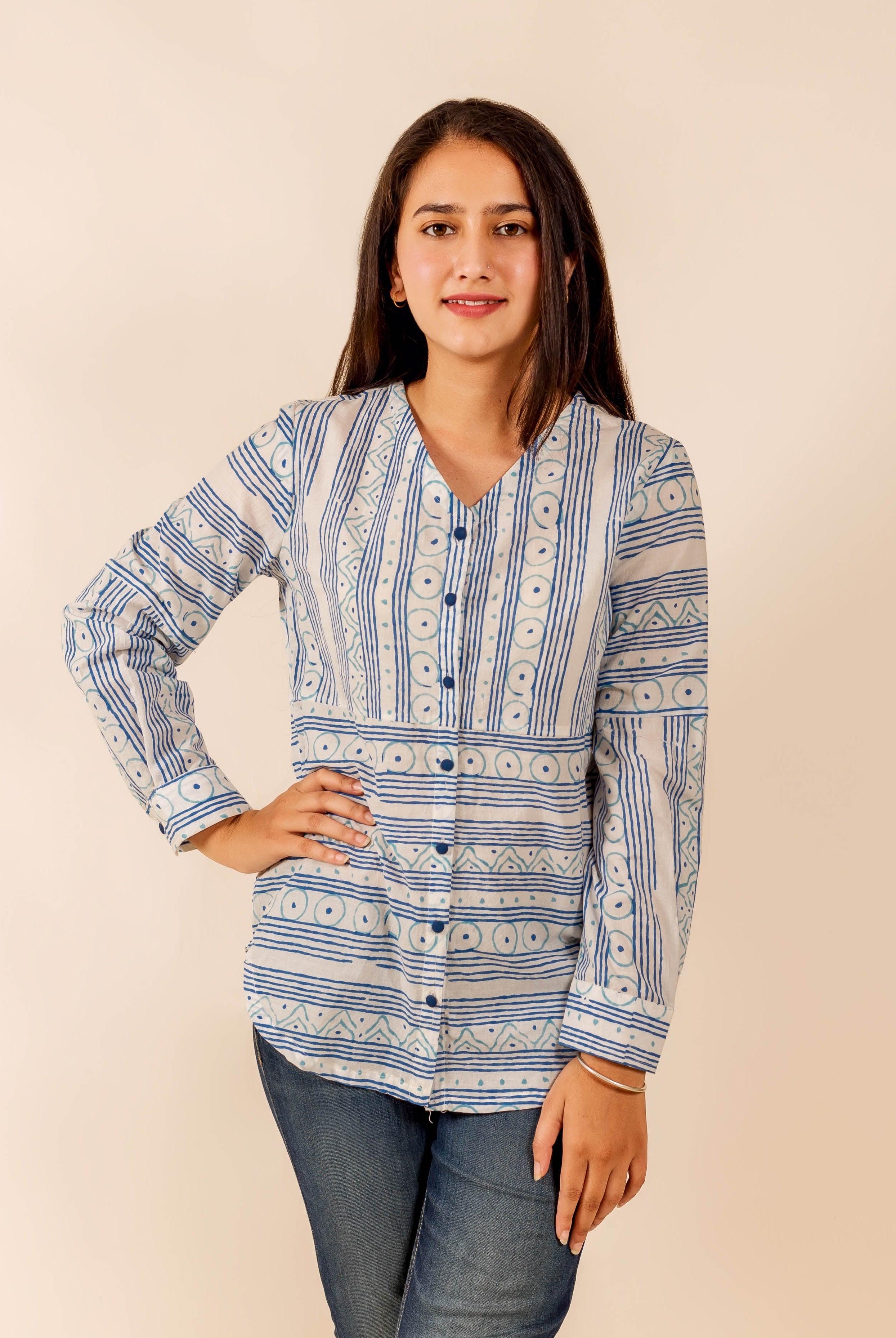 Standing young woman in a white and blue ethnic block-printed long-sleeve shirt.