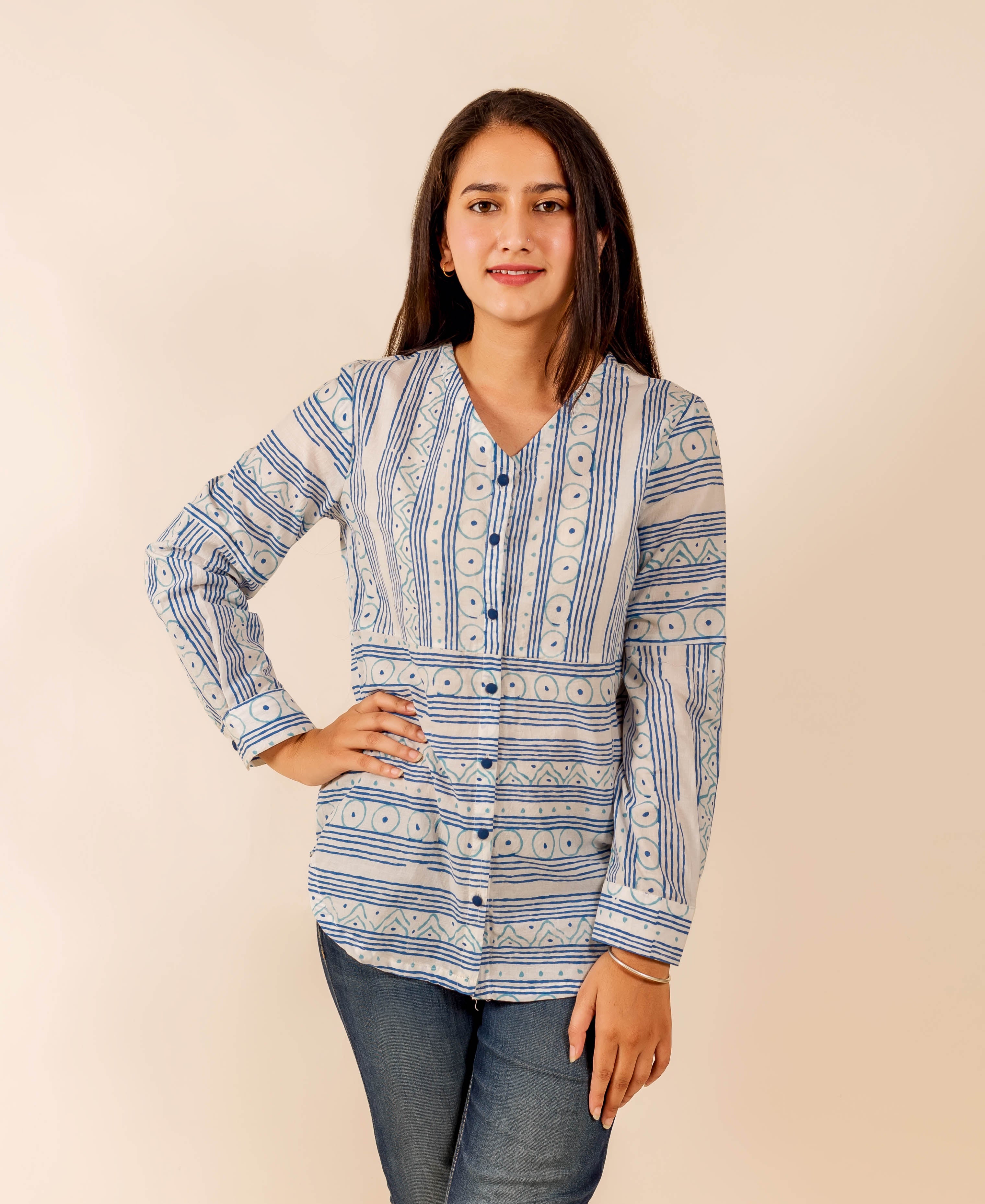 Standing young woman in a white and blue ethnic block-printed long-sleeve shirt.