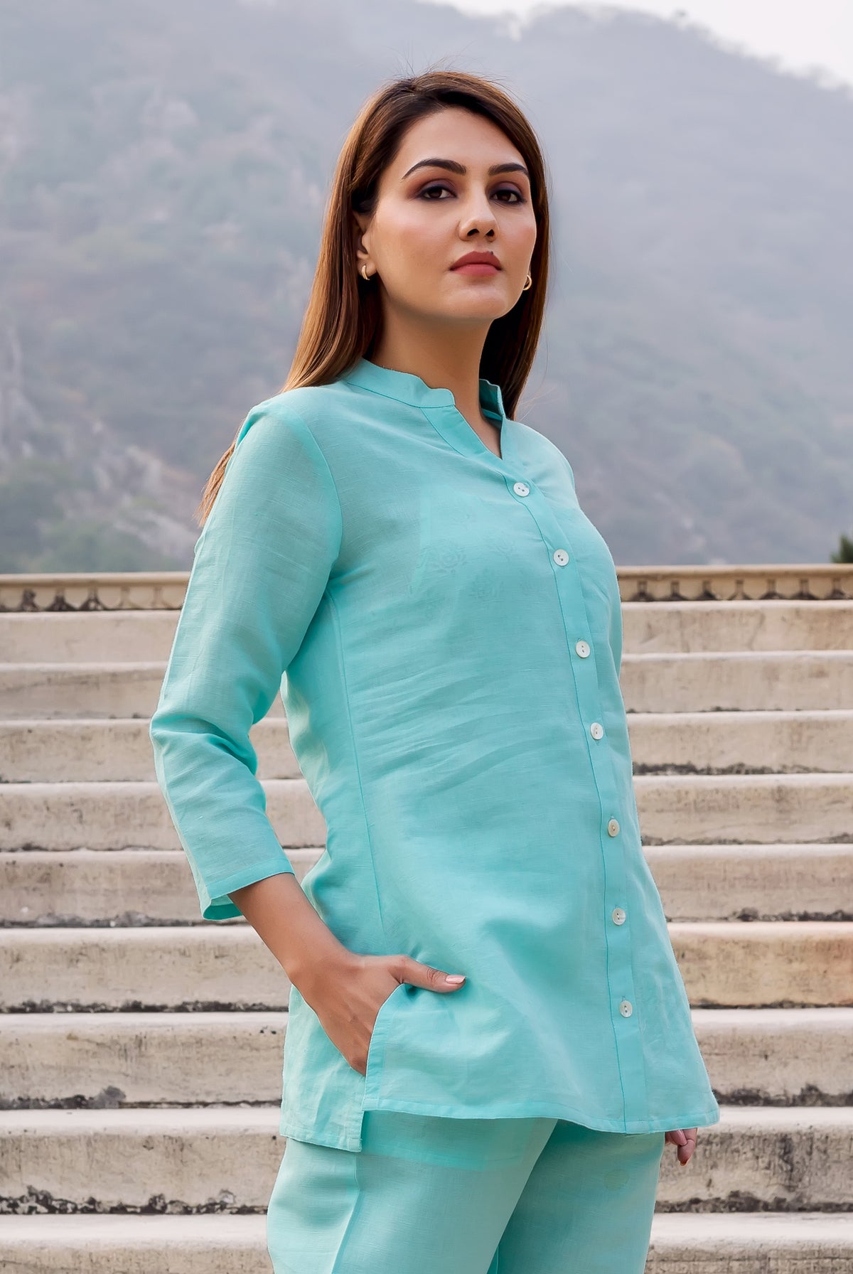 Baby blue linen top with white buttons and mandarin collar on a woman outdoors.