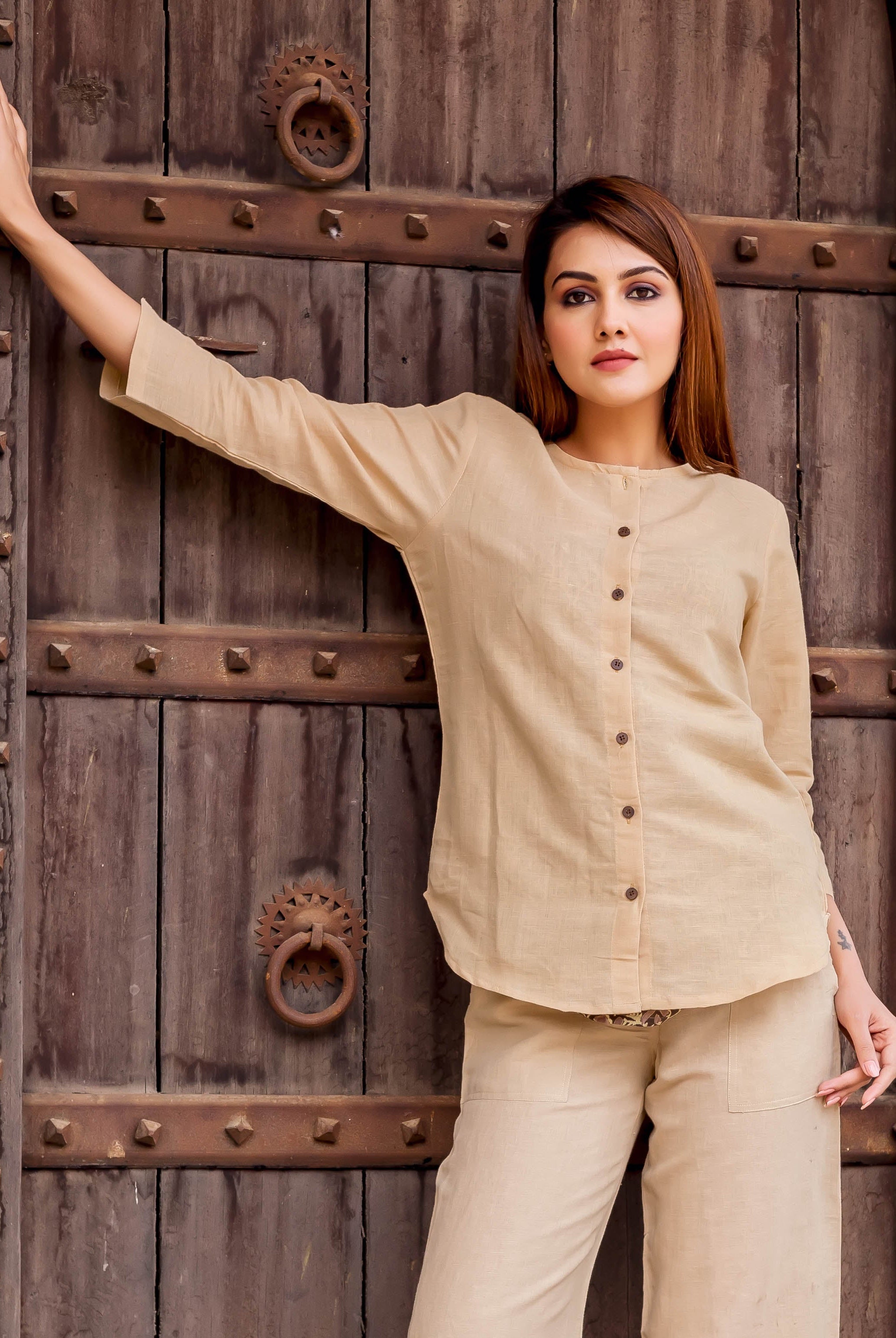 Front view of a model wearing a beige linen button-down top with 3/4 sleeves.