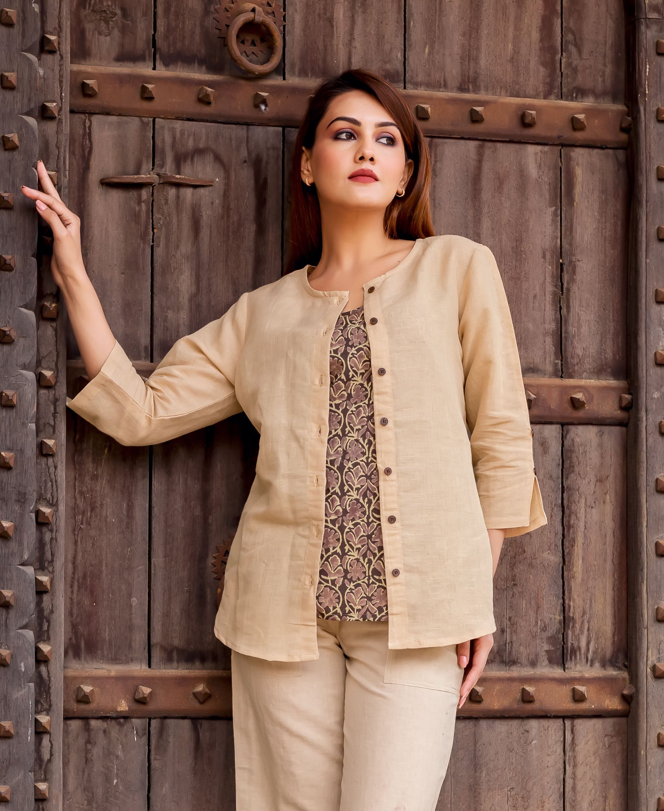 Beige linen button-down top on model, revealing dark ethnic floral print undershirt.
