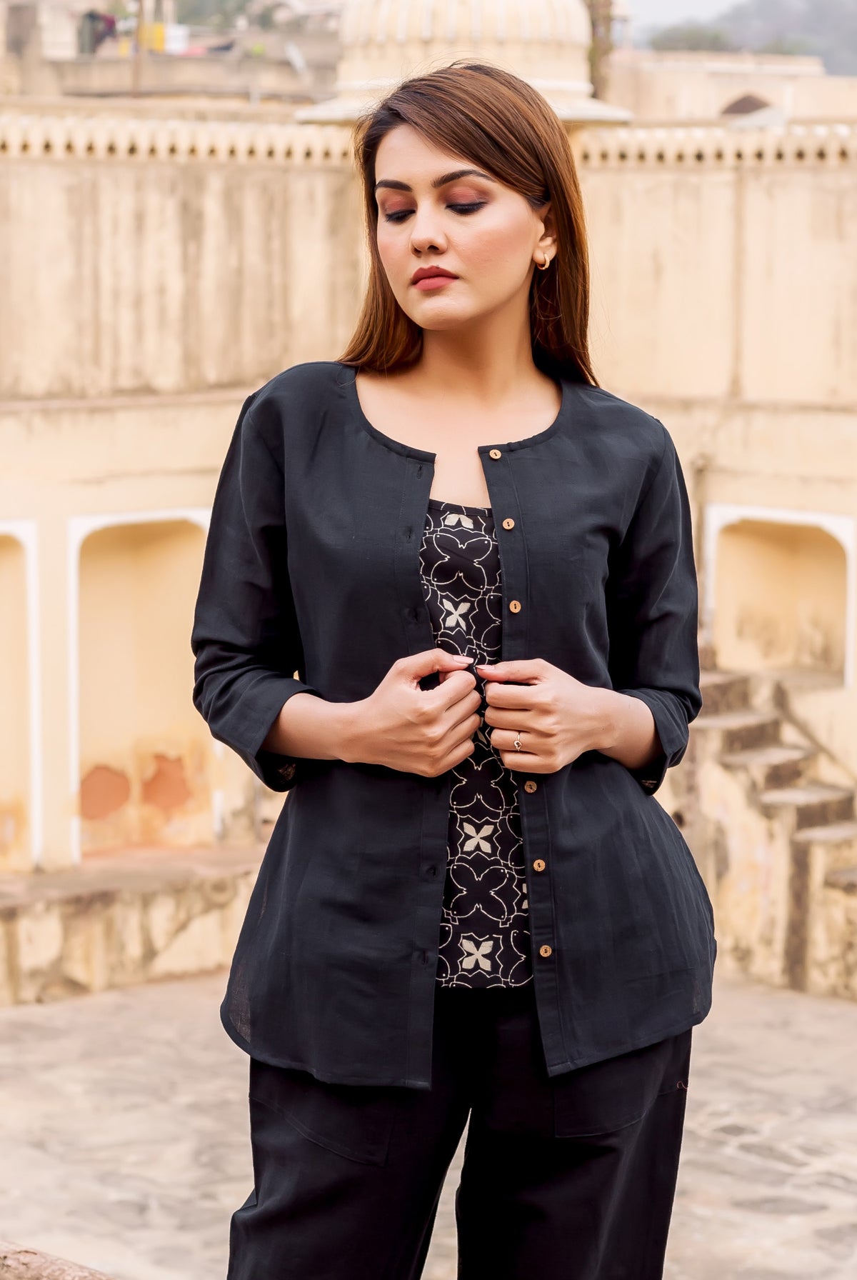 A woman wearing a black linen button-down top with a white floral print.