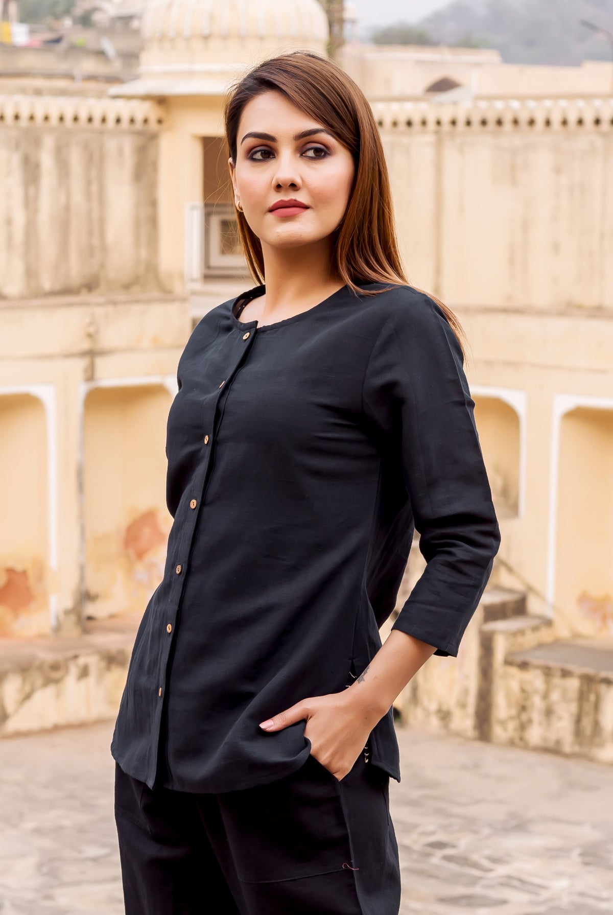 Model in a black button-down top, front view, with three-quarter sleeves and subtle buttons.