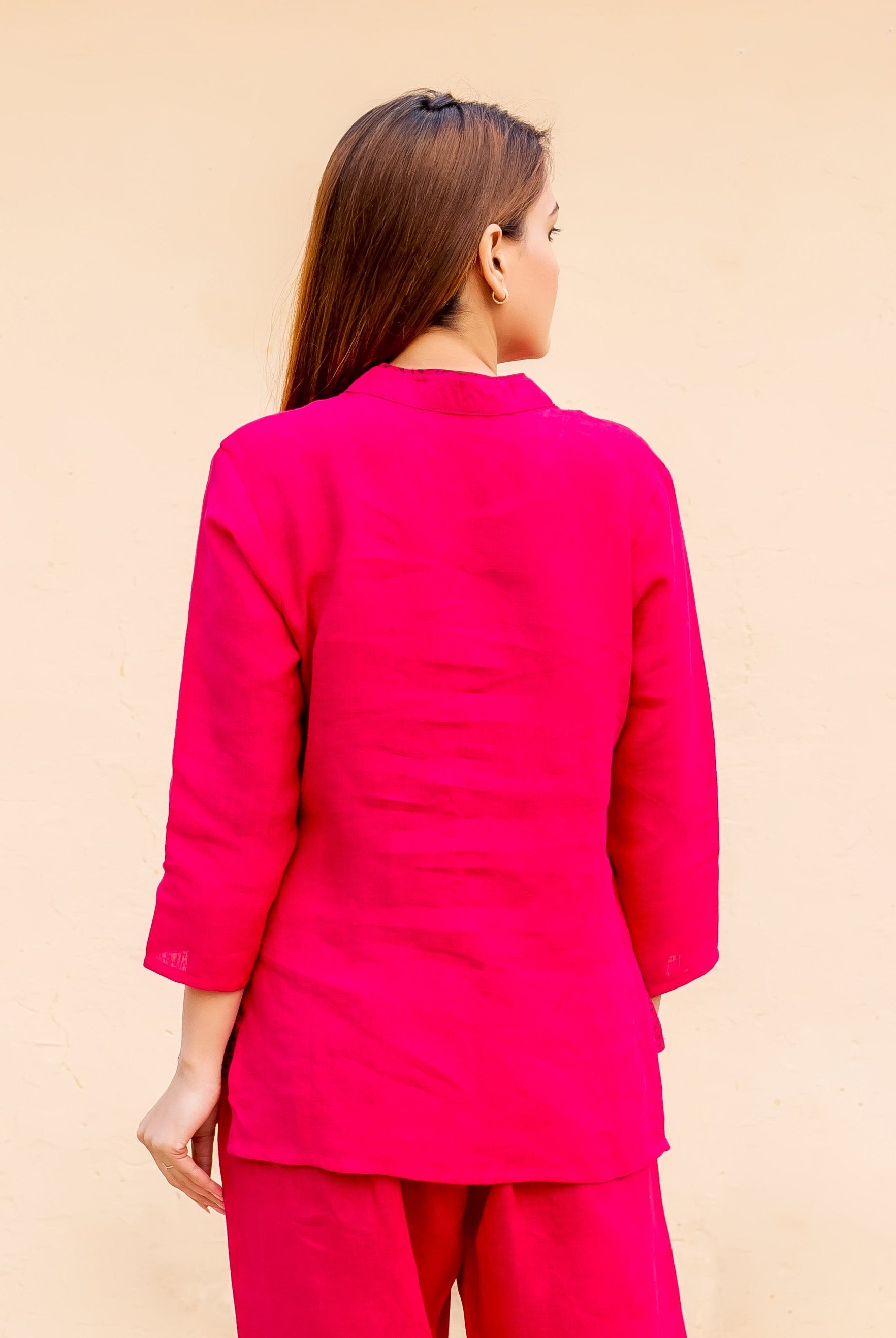 Back view of a model wearing a ruby pink linen top with ethnic block print.