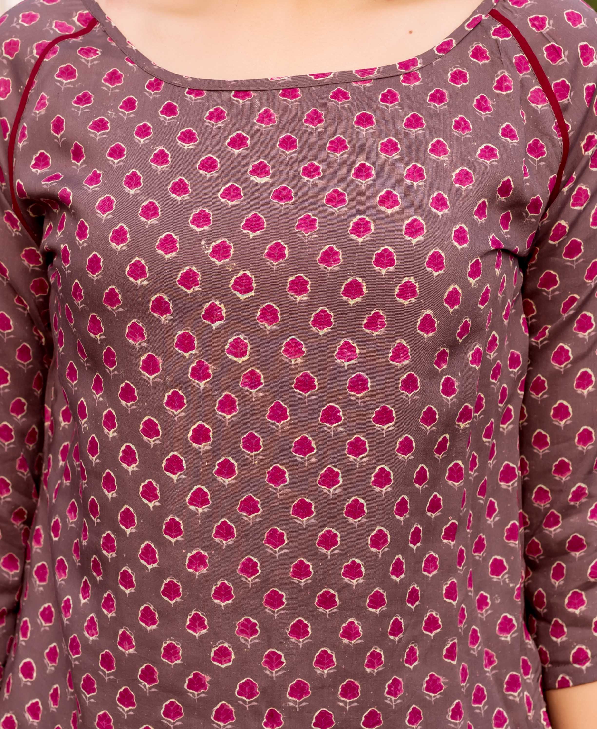 Front close-up of brown hand block printed top with magenta floral motifs and red piping.