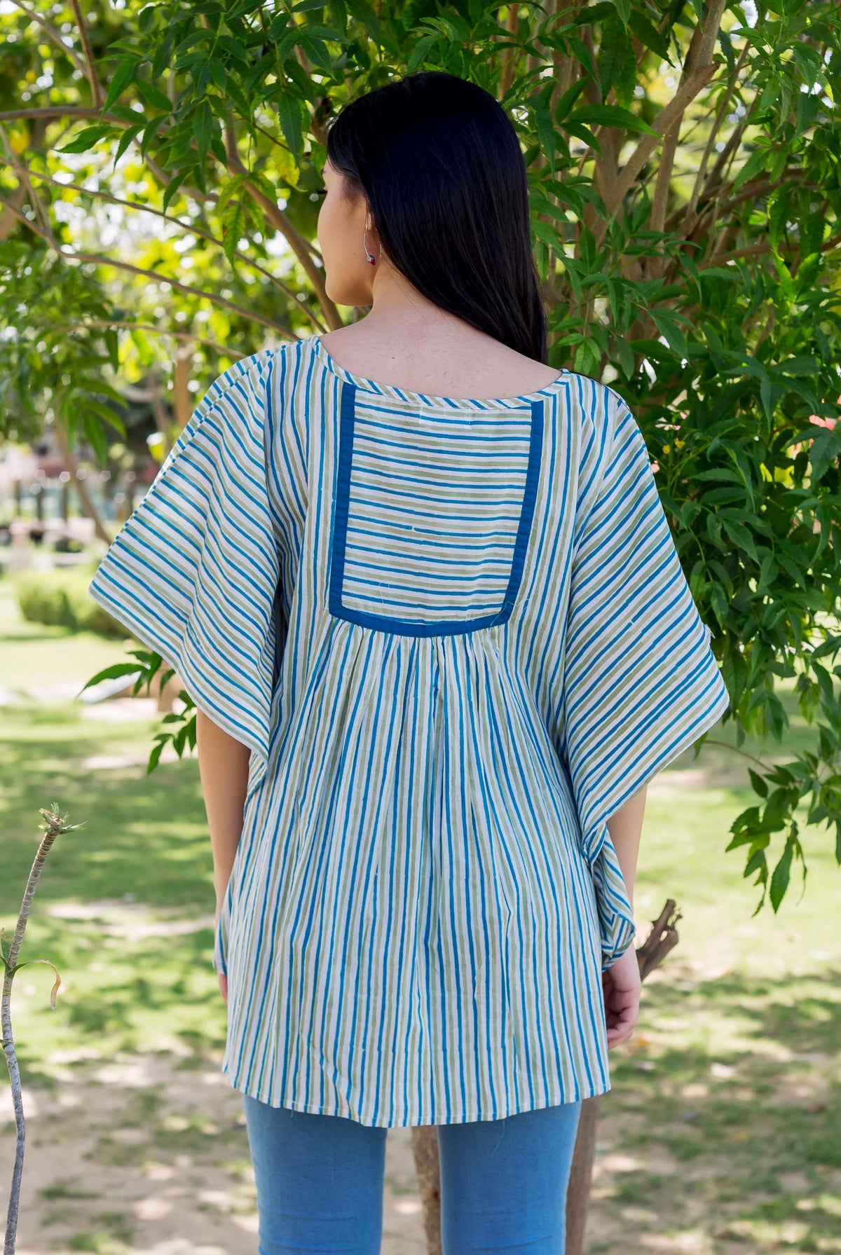 Rear view of model in blue, green striped block print kaftan top with square yoke.