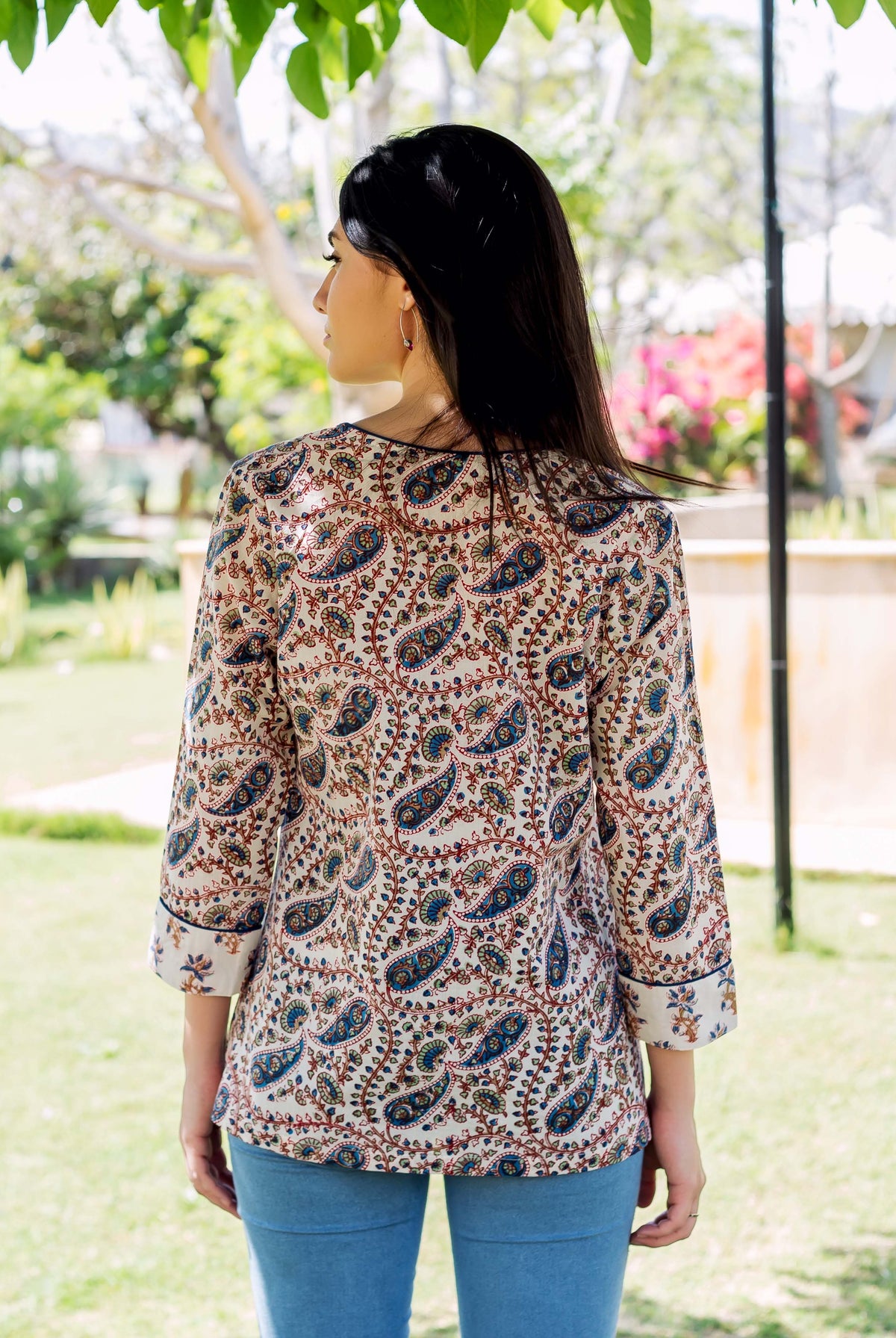 Back of model in white hand-block-printed paisley top with blue and brown patterns.