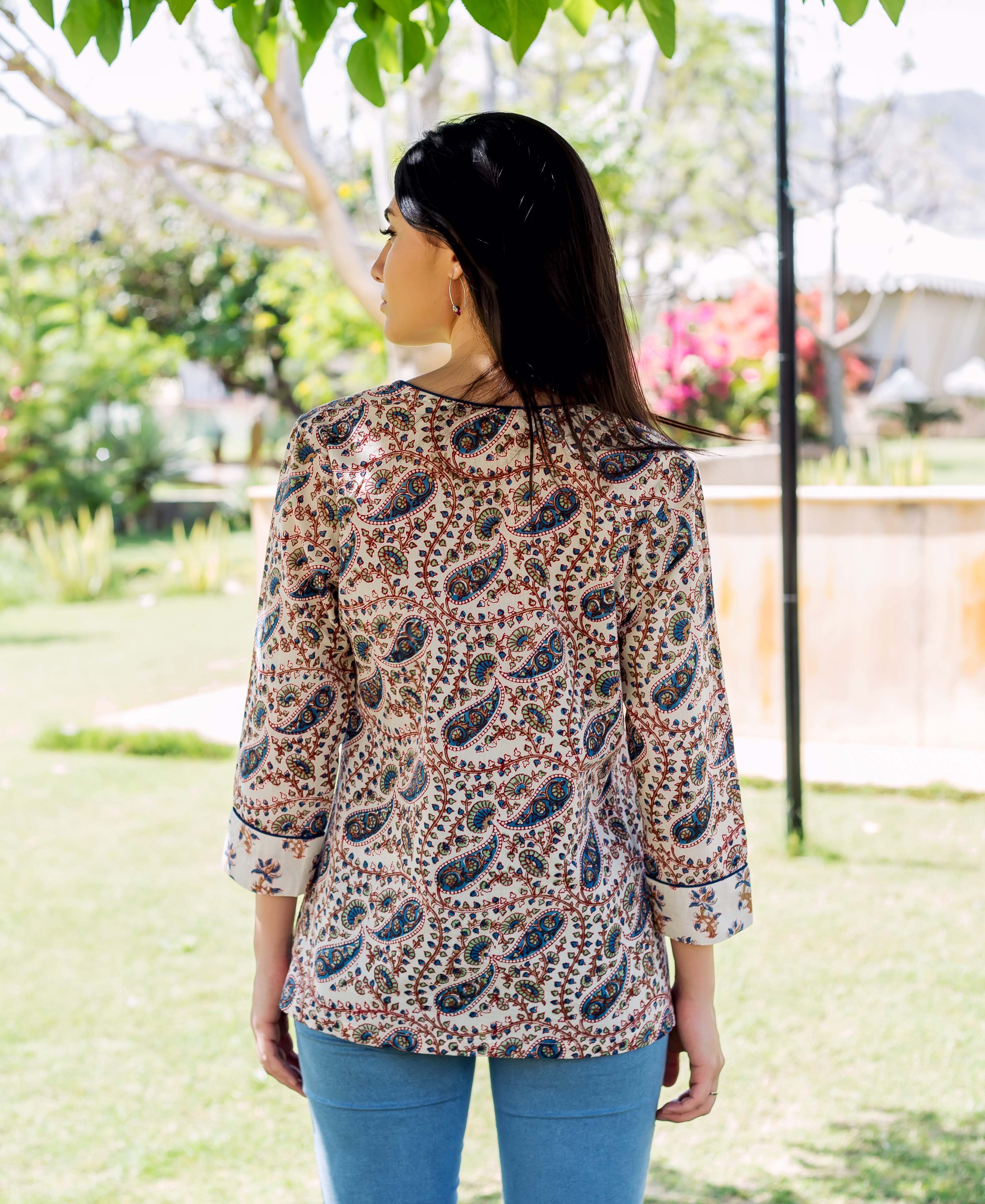 Back of model in white hand-block-printed paisley top with blue and brown patterns.