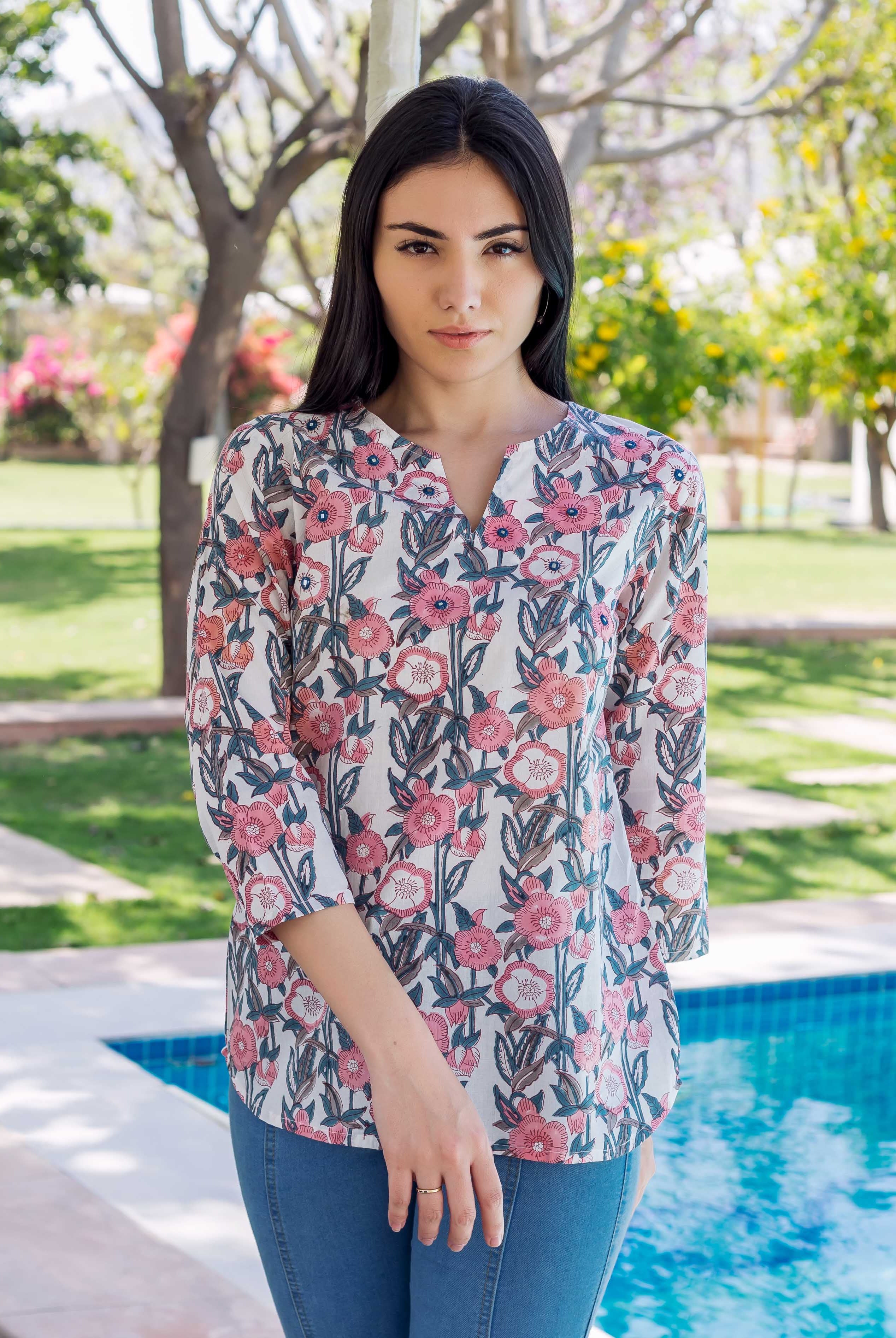 Model in white, pink, and grey block-printed floral tunic, standing by a pool.