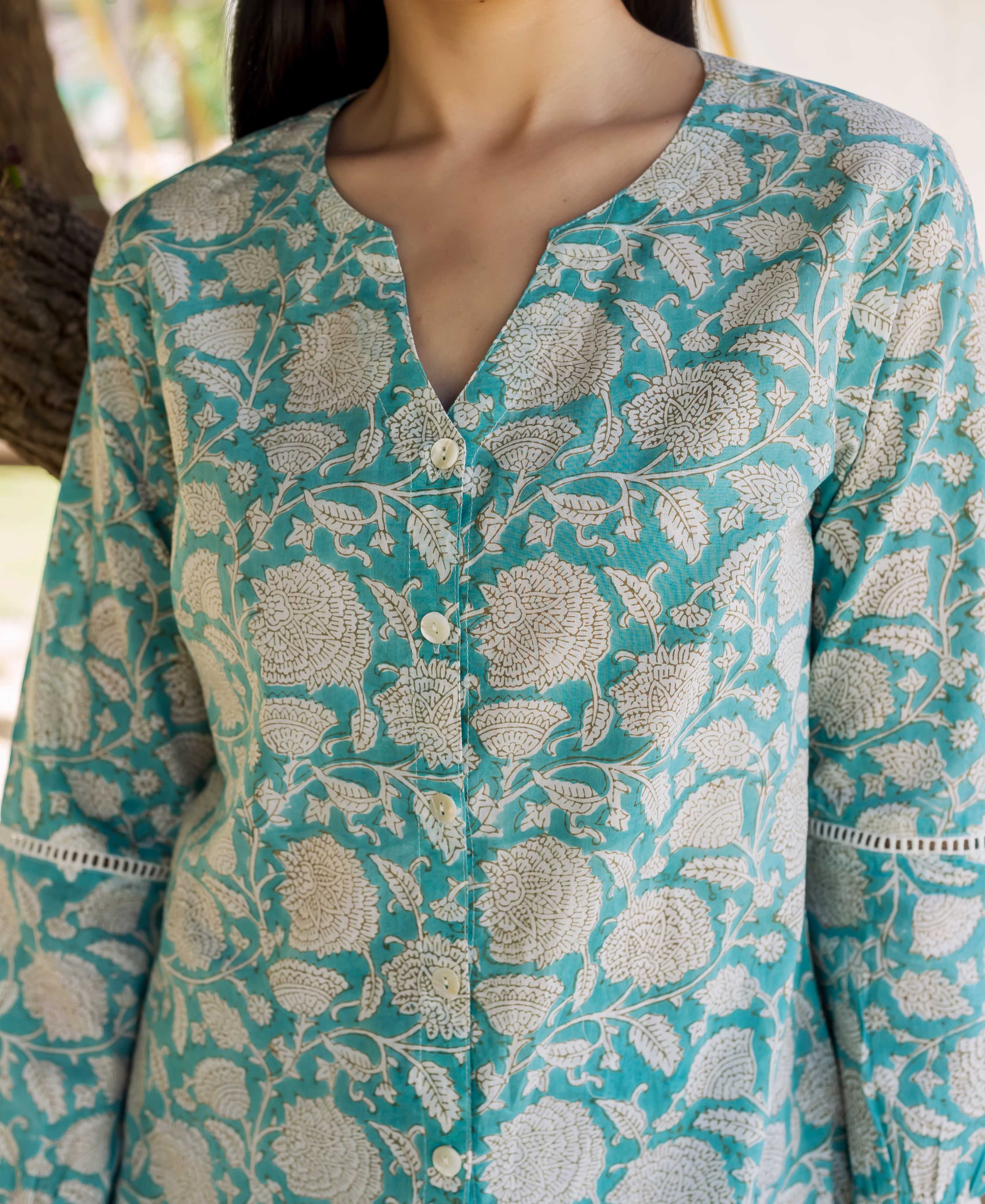 Front close-up of model wearing teal hand block printed button-down top with white florals and lace sleeves.
