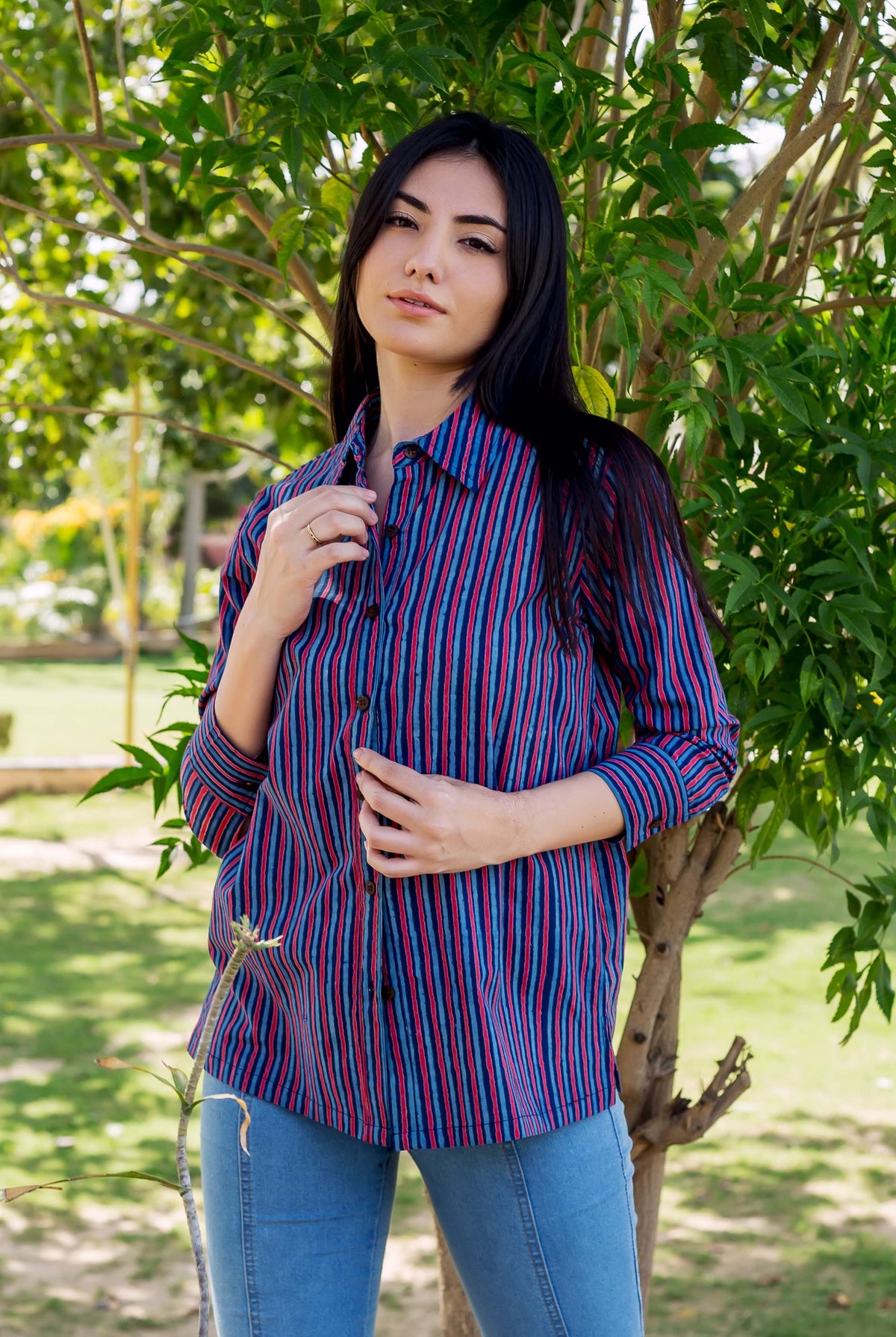 A model wearing a blue and red striped shirt with a collar and buttons.