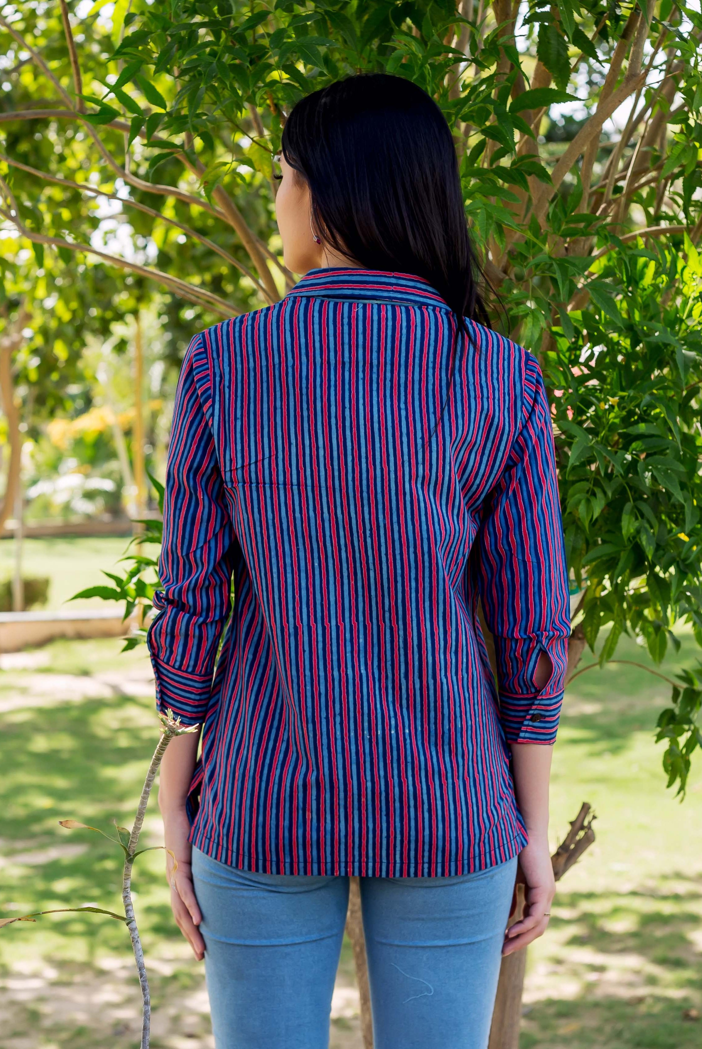 A model wearing a blue and red striped shirt with a collar and long sleeves.