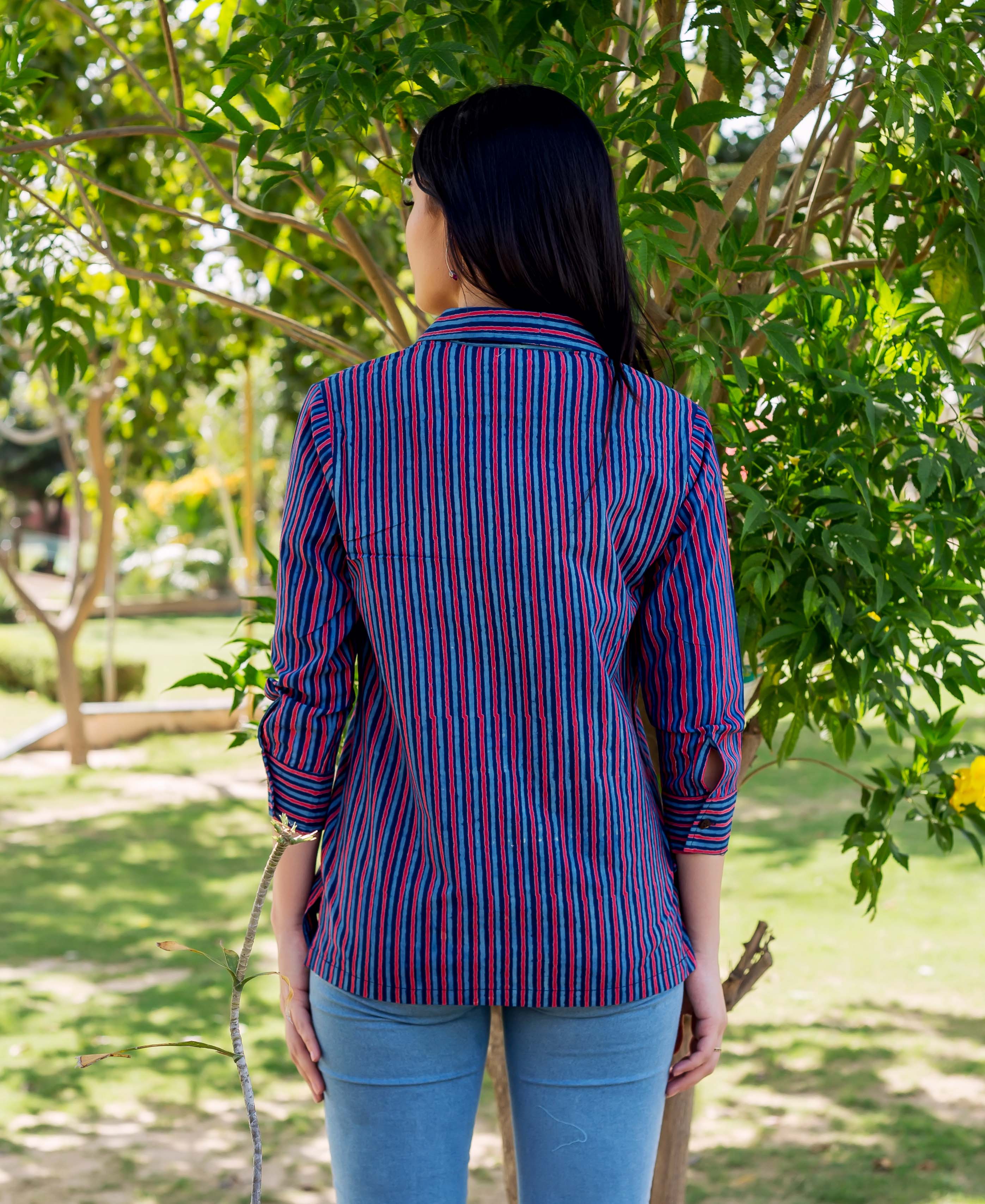 A model wearing a blue and red striped shirt with a collar and long sleeves.